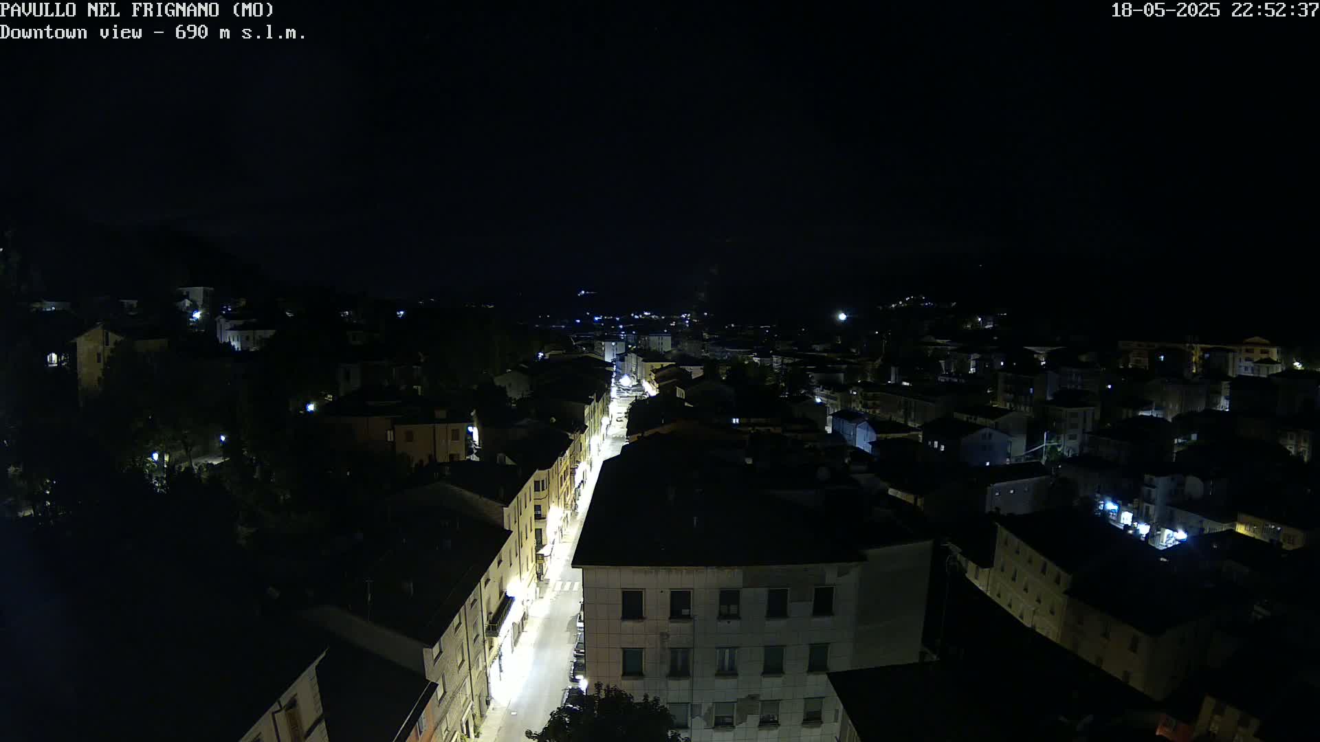 A nighttime, high-angle view shows a town's streets and buildings illuminated by artificial lights.