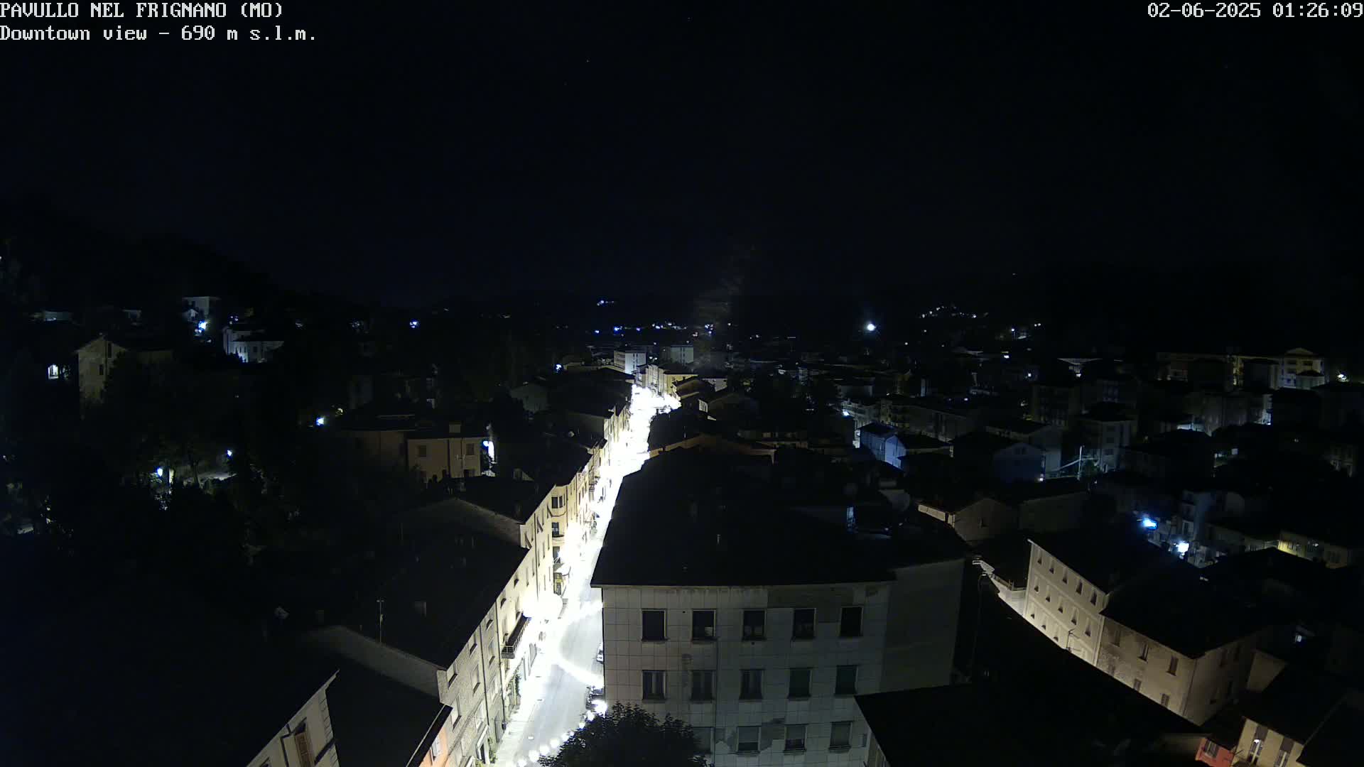 A nighttime, high-angle view of a town's illuminated streets and buildings under a clear, dark sky.