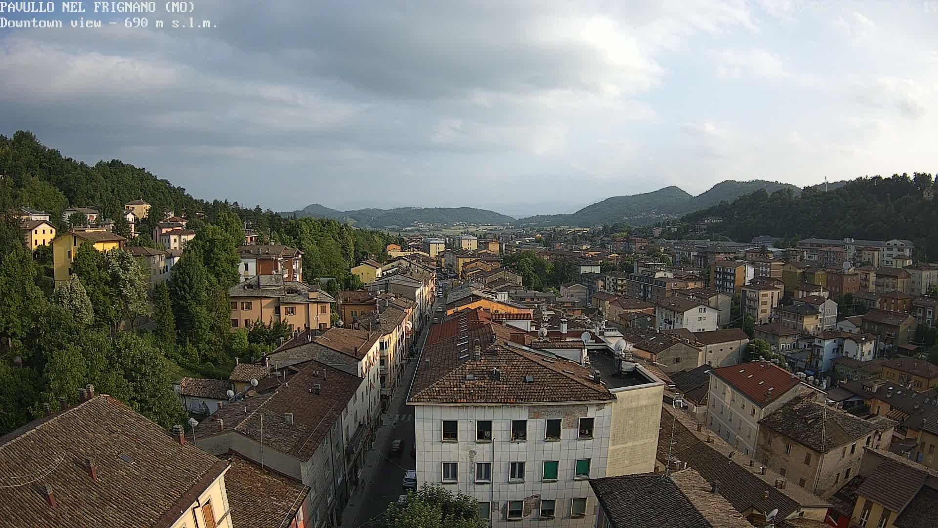 An aerial view of a town nestled in a valley, under a partly cloudy sky.