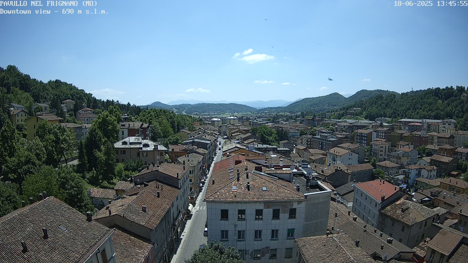An aerial view of a town nestled in a valley, under a clear blue sky.