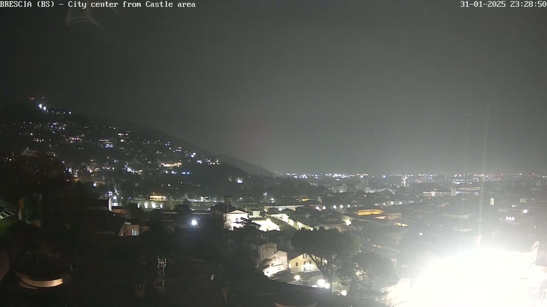 A nighttime view of a city on a hill under a dark, overcast sky.