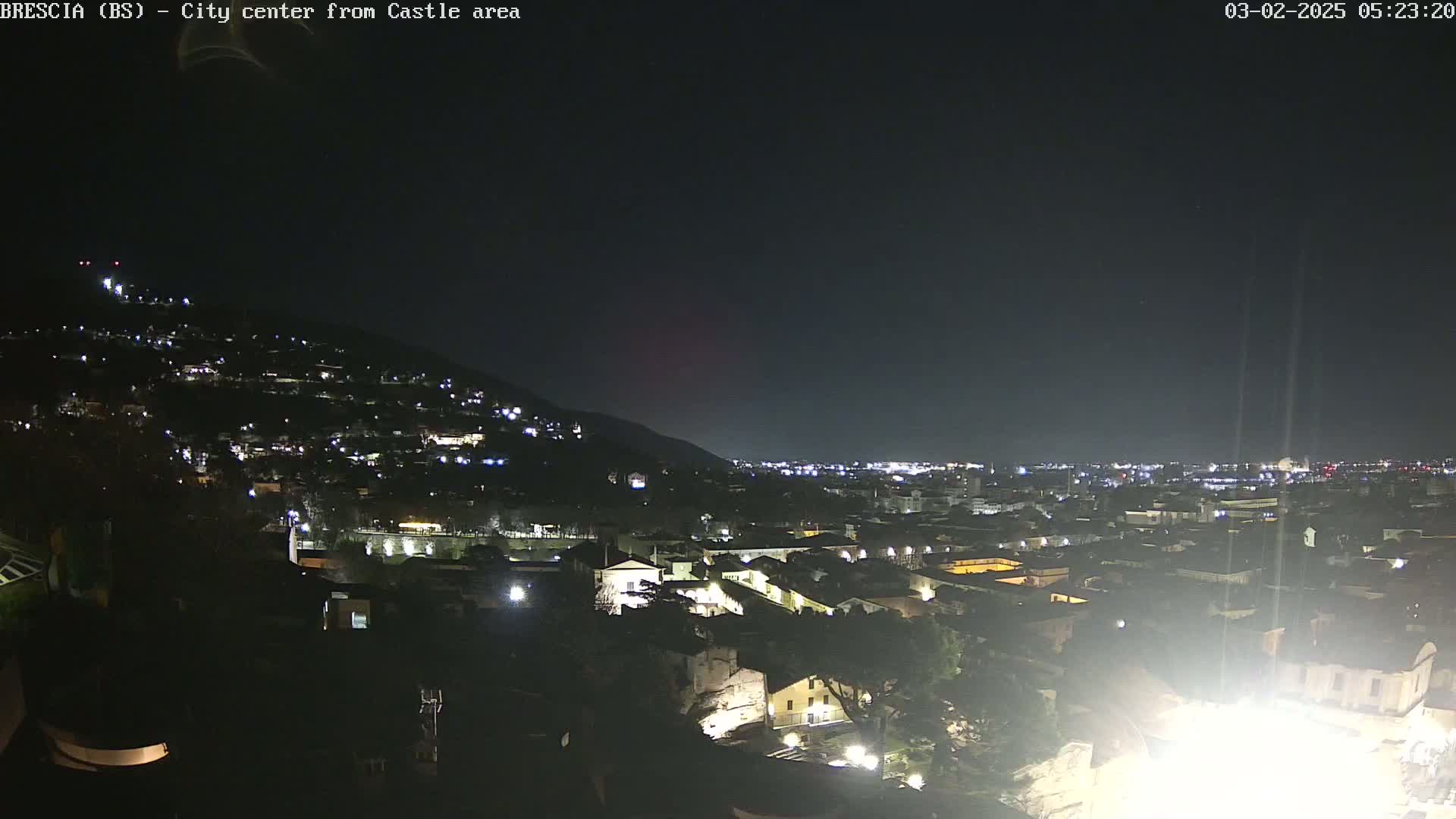 A nighttime view of a city nestled against a hill, under a clear, dark sky.