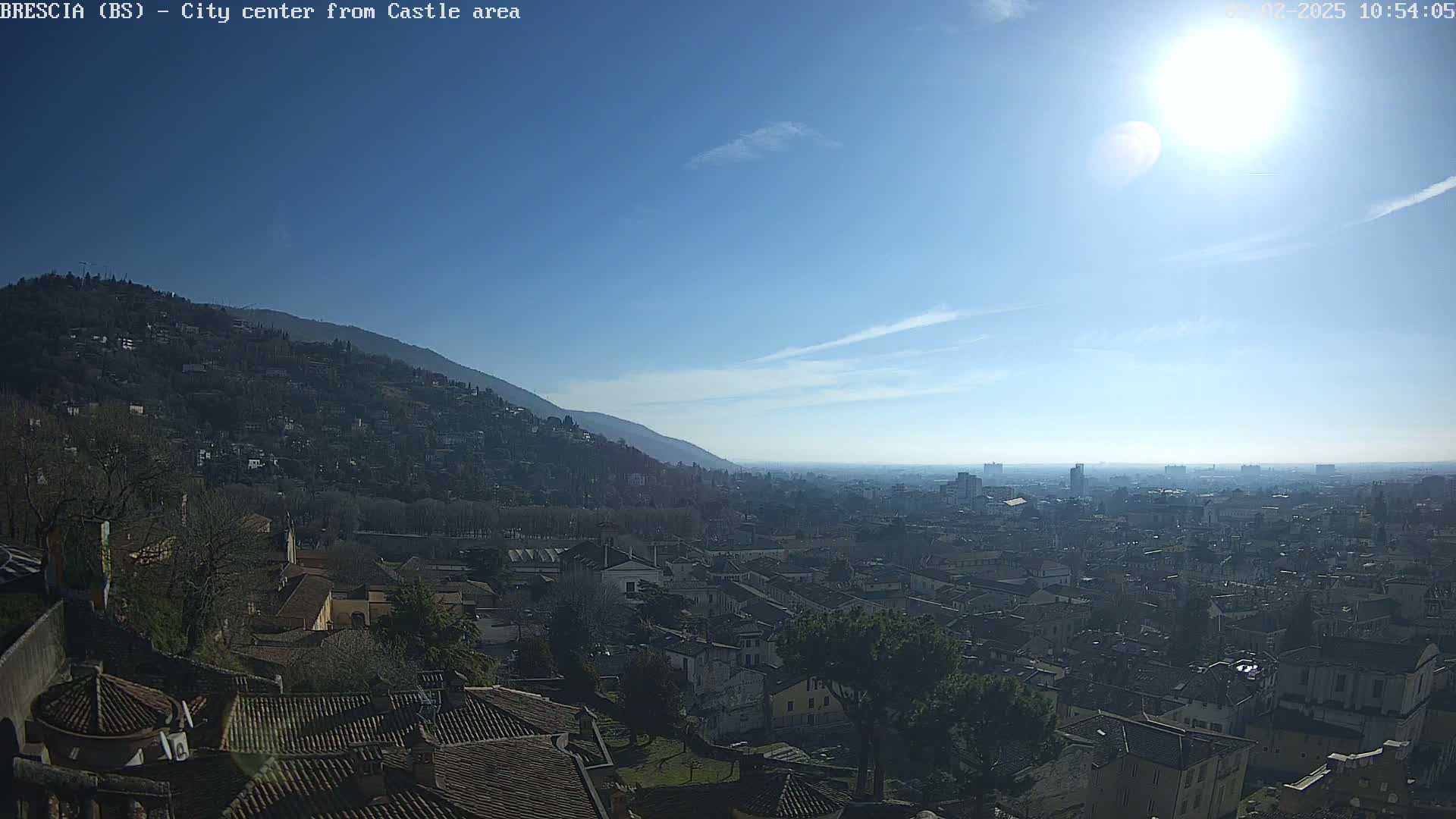 A sunny day reveals a sprawling city nestled in a valley, with a mountain rising behind it.
