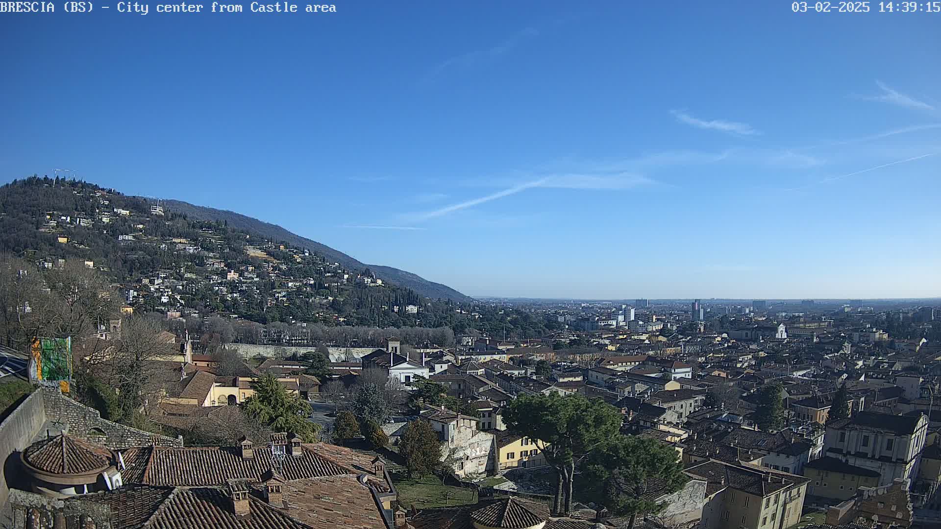 A sprawling city nestled against a mountainside under a clear blue sky.