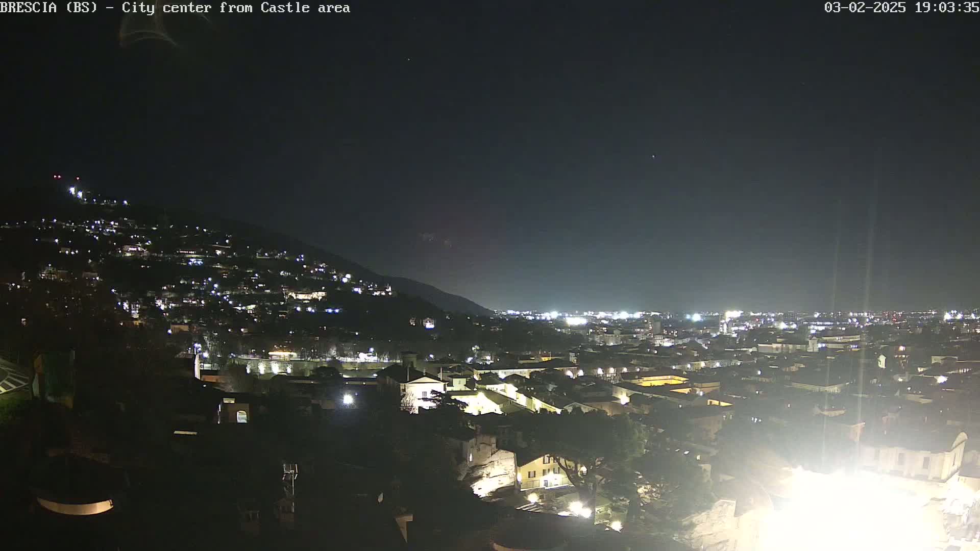 A nighttime, long shot of a city illuminated by lights against a dark, clear sky.