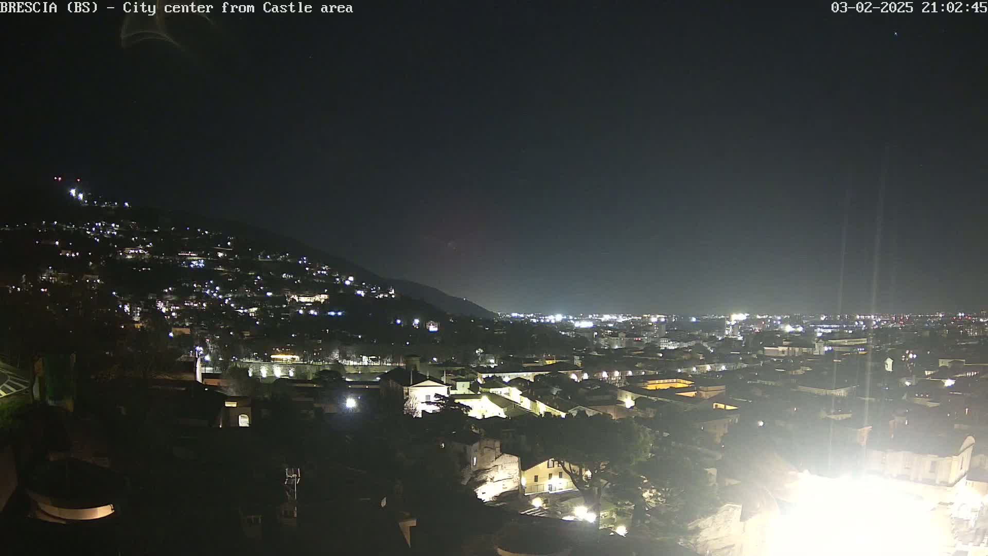 A nighttime view of a city sprawling across a hillside, under a clear, dark sky.