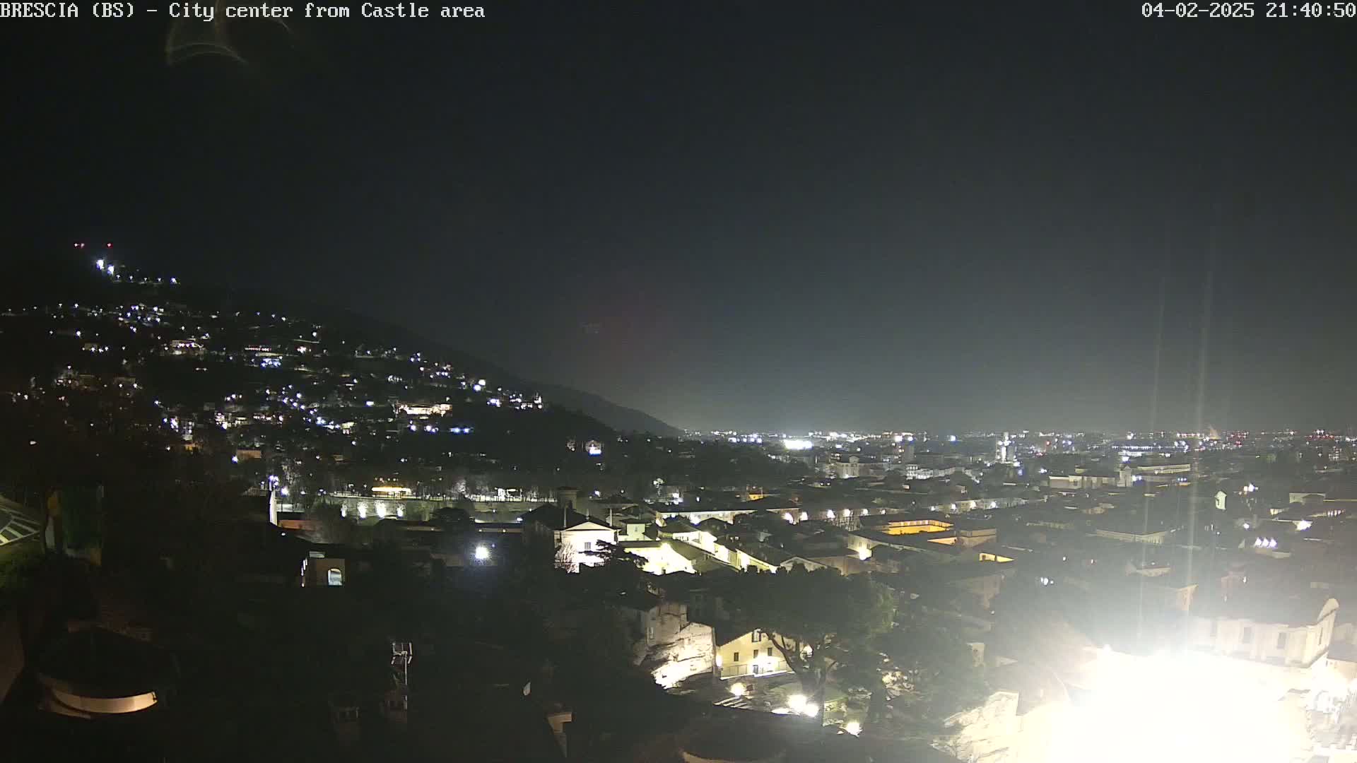 A nighttime, long shot of a city on a hillside under a dark, clear sky.