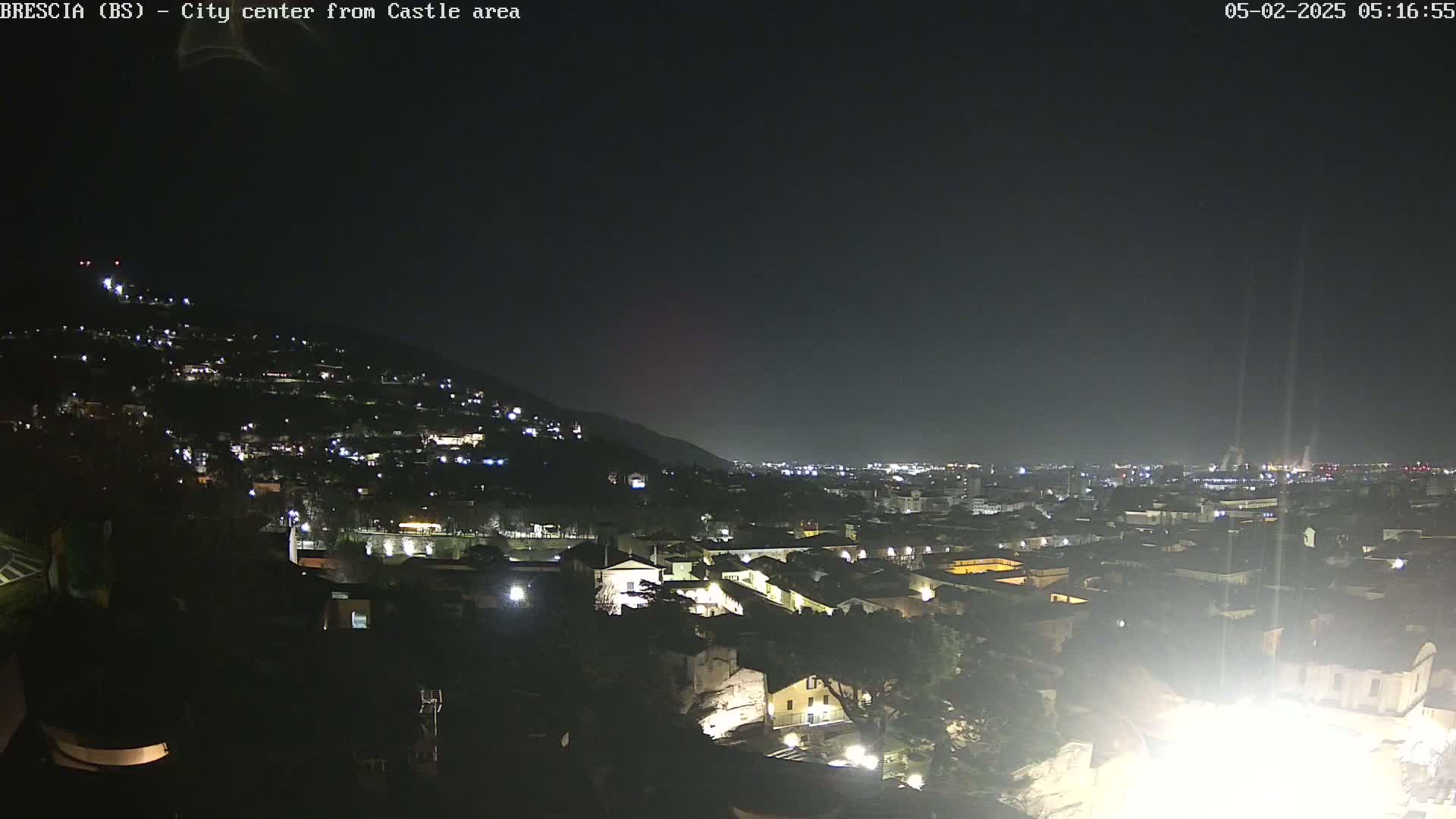A nighttime, long shot of a city sprawling across a hillside, illuminated by scattered lights.