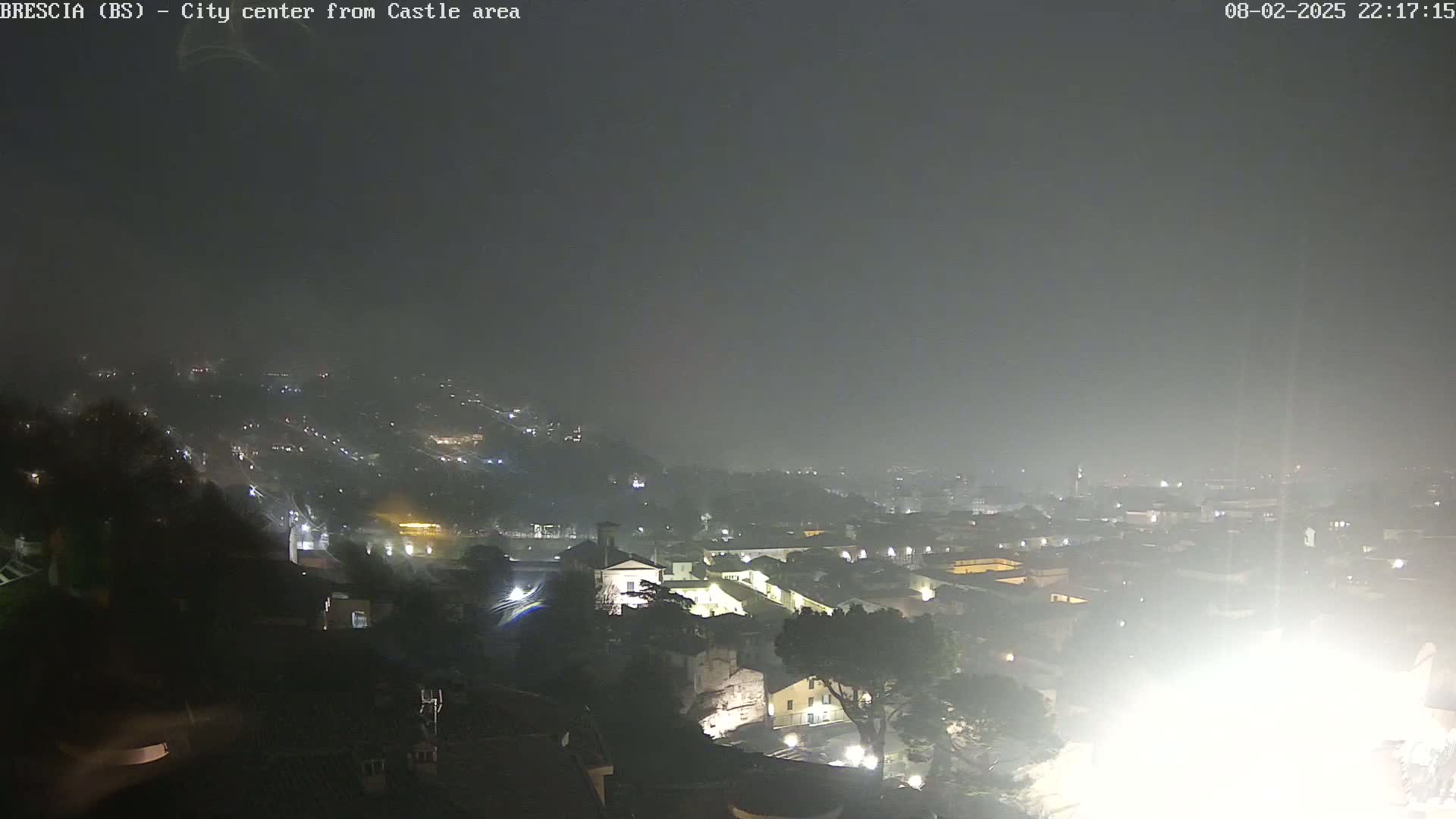 A nighttime, hazy view of a city illuminated by streetlights and buildings, seen from an elevated vantage point.