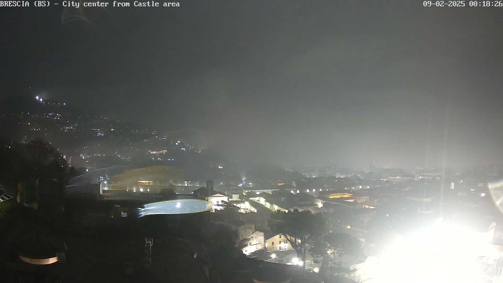 A nighttime view of a city shrouded in fog, showing dimly lit buildings and streets.