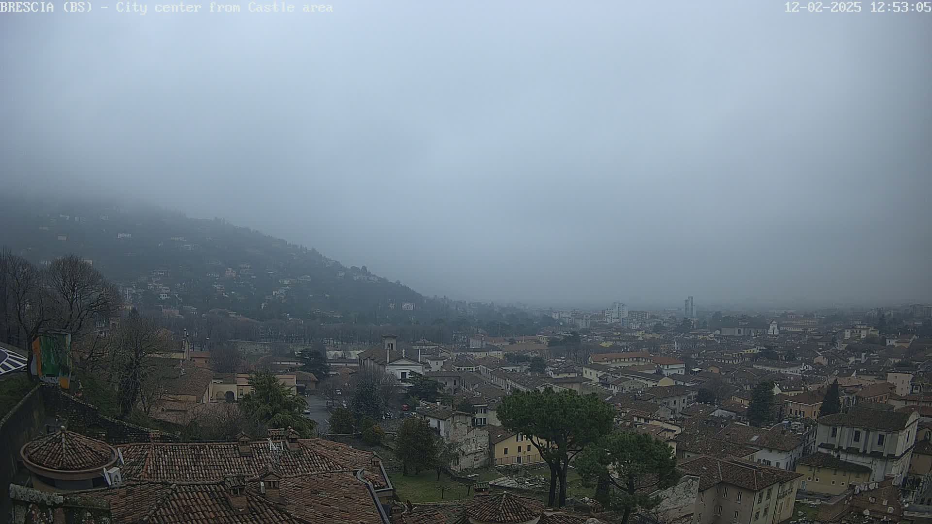 A foggy view of a city nestled in a valley, surrounded by hills.