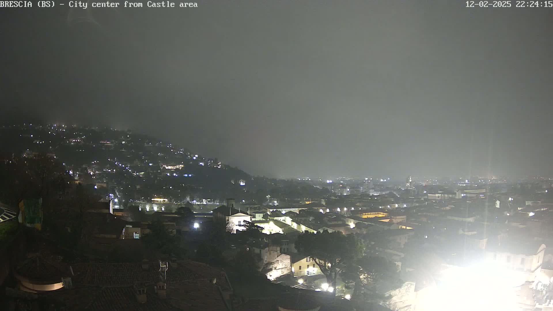 A nighttime view of a city nestled on a hill, shrouded in a hazy, overcast atmosphere.
