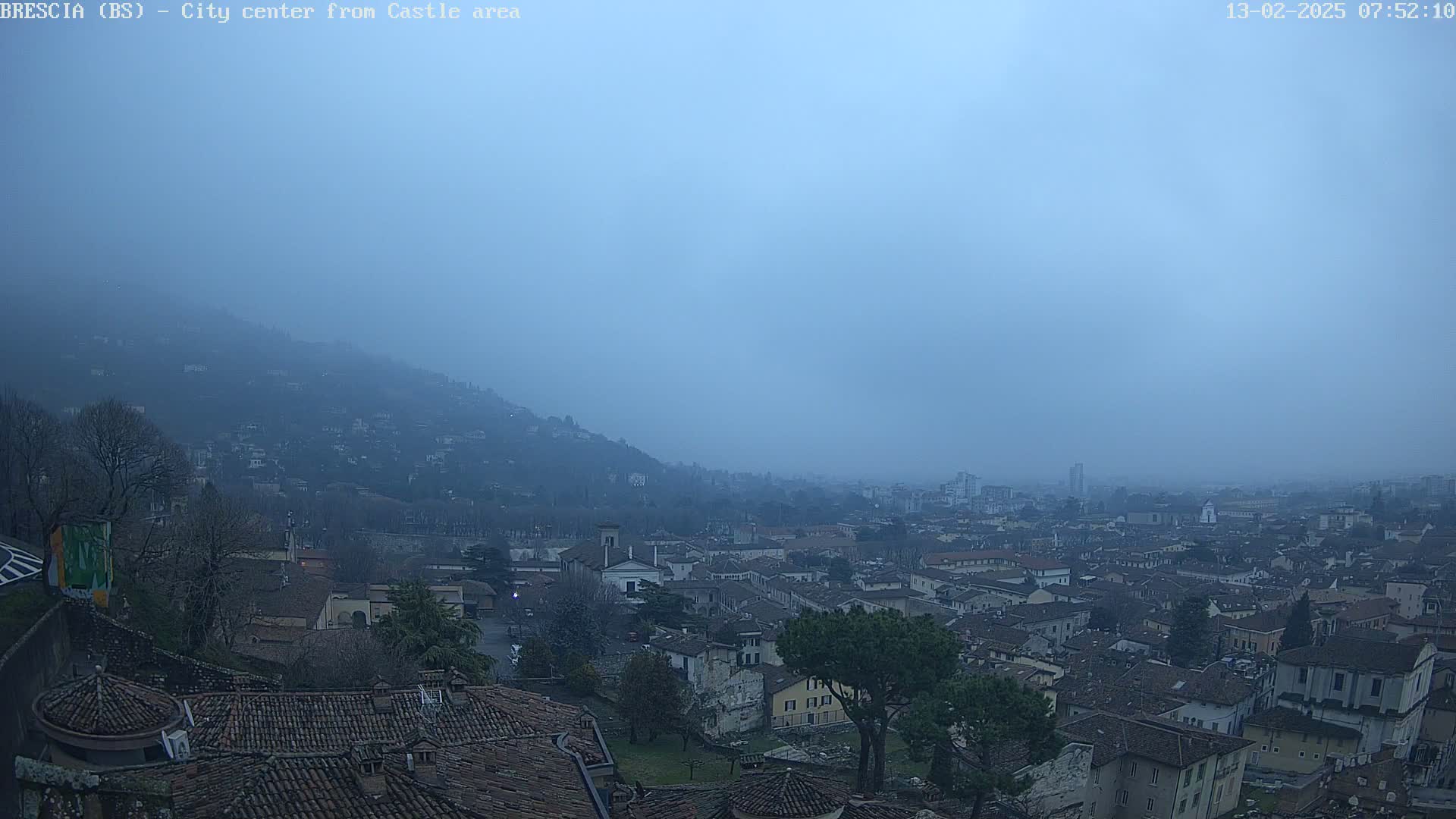 A hazy, overcast view of a city nestled in a valley, with hills rising in the background.