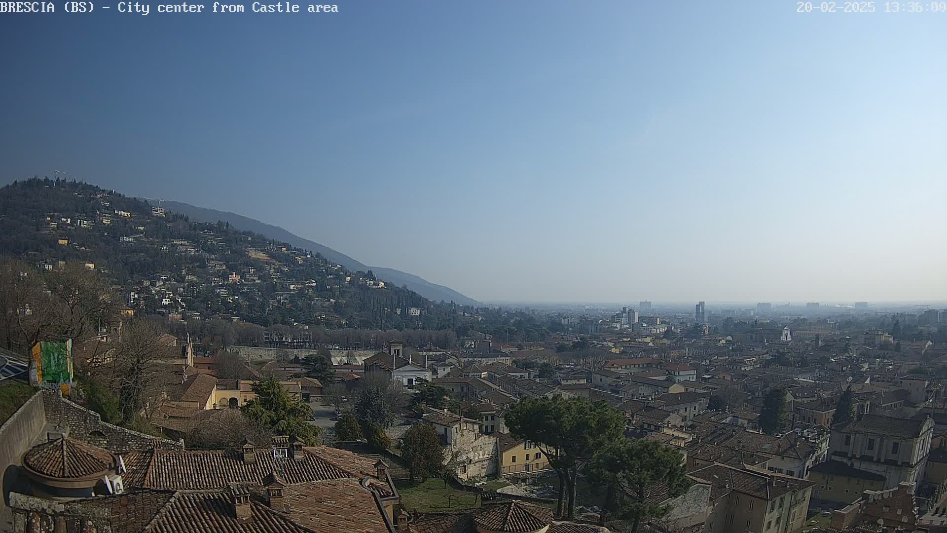 A sprawling city nestled against a mountainside under a clear, sunny sky.