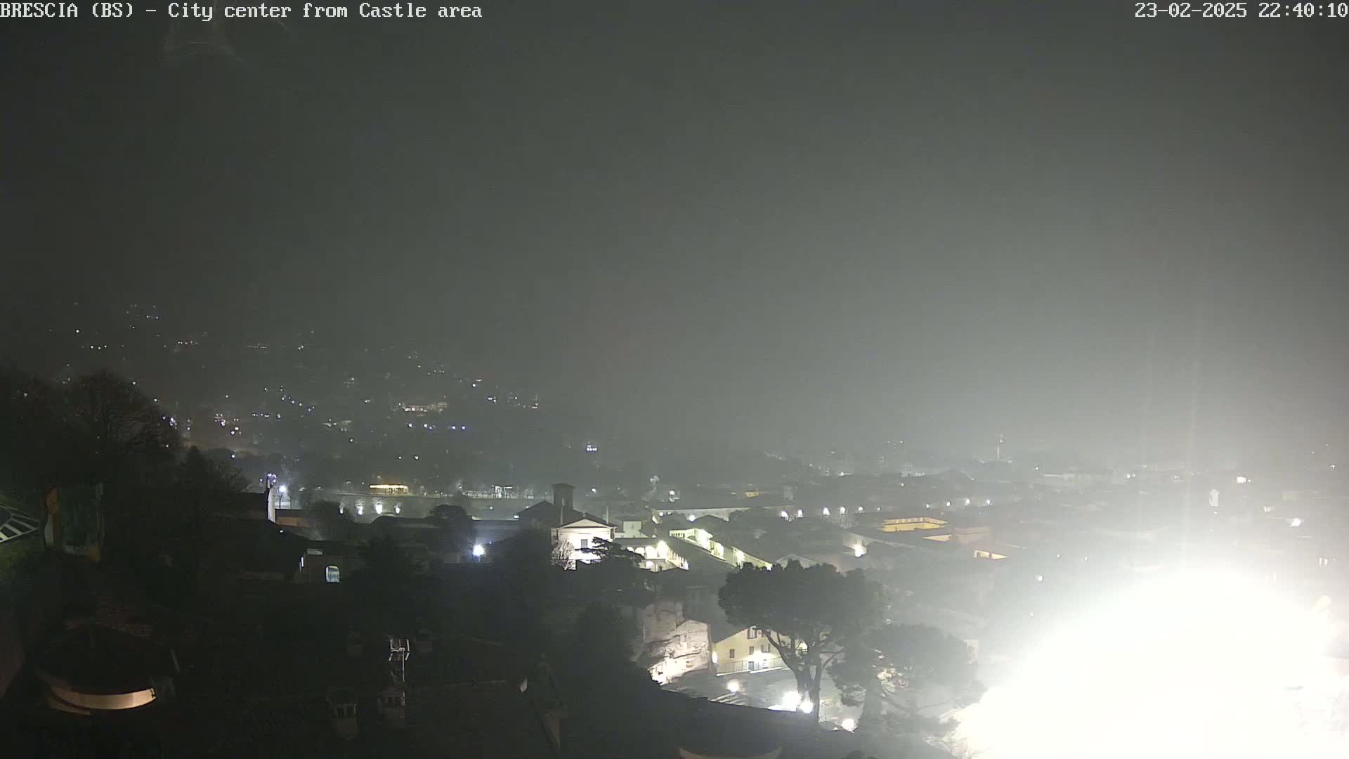 A hazy, nighttime view of a city's lights and buildings, seen from a higher vantage point.