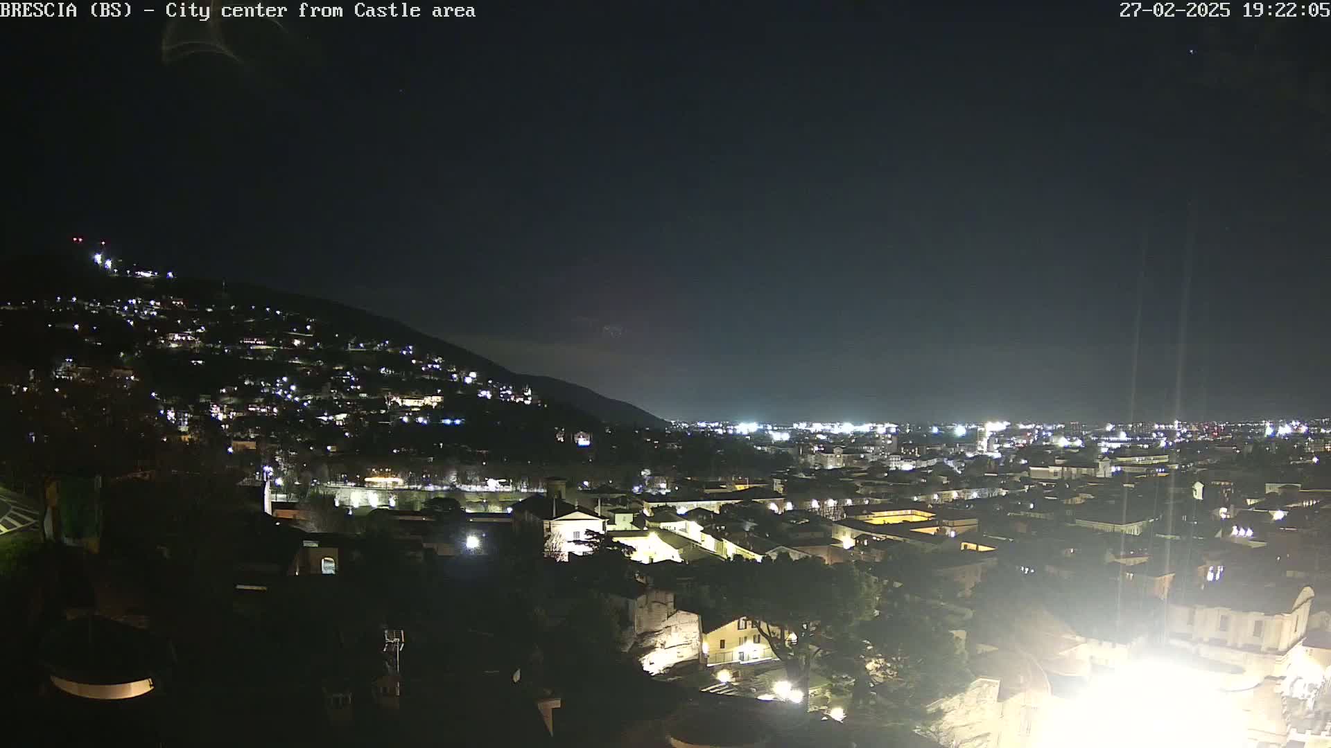 A nighttime, high-angle view of a city illuminated by lights against a dark, clear sky.