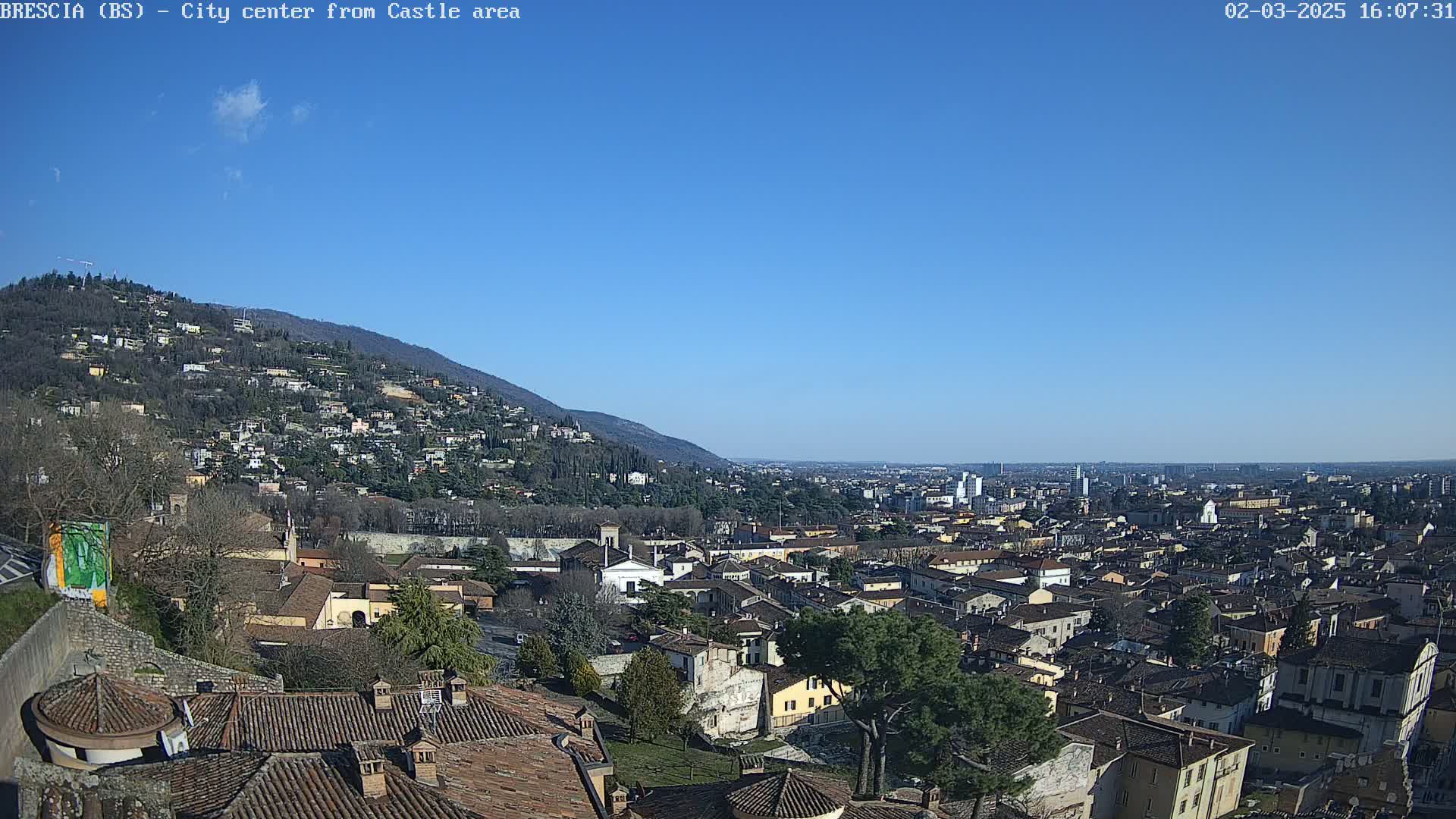 A sprawling city nestled at the foot of a mountain under a clear blue sky.