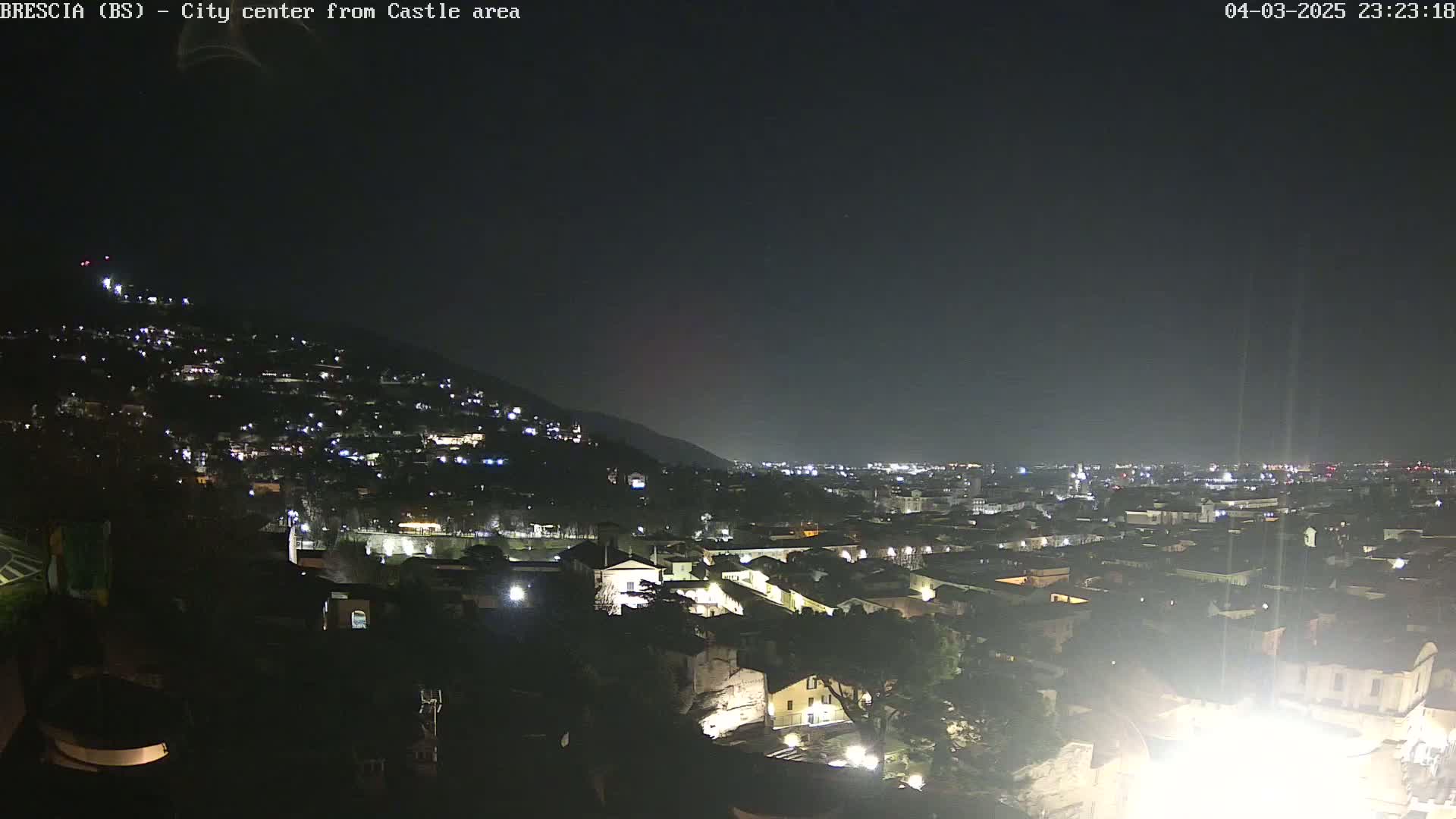 A nighttime, long shot of a city nestled into a hillside, under a clear, dark sky.