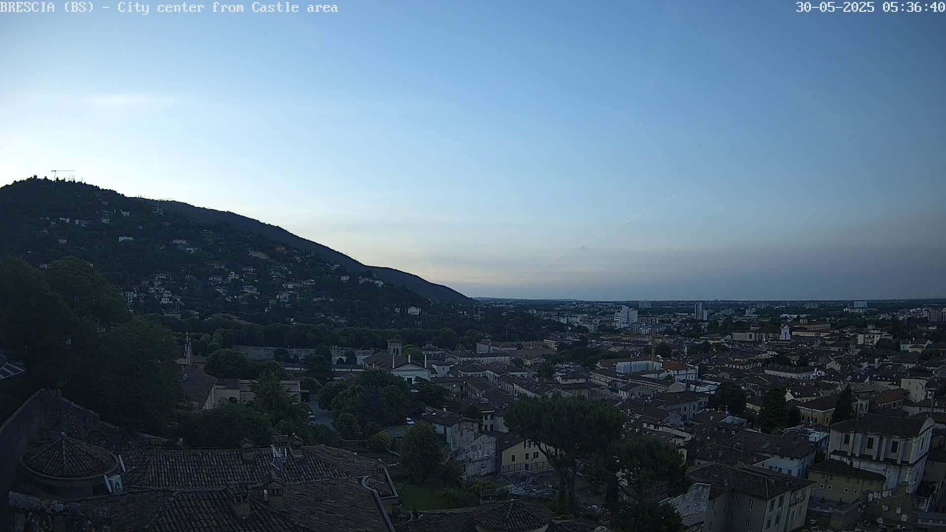 A city sprawls beneath a hill under a clear, twilight sky.