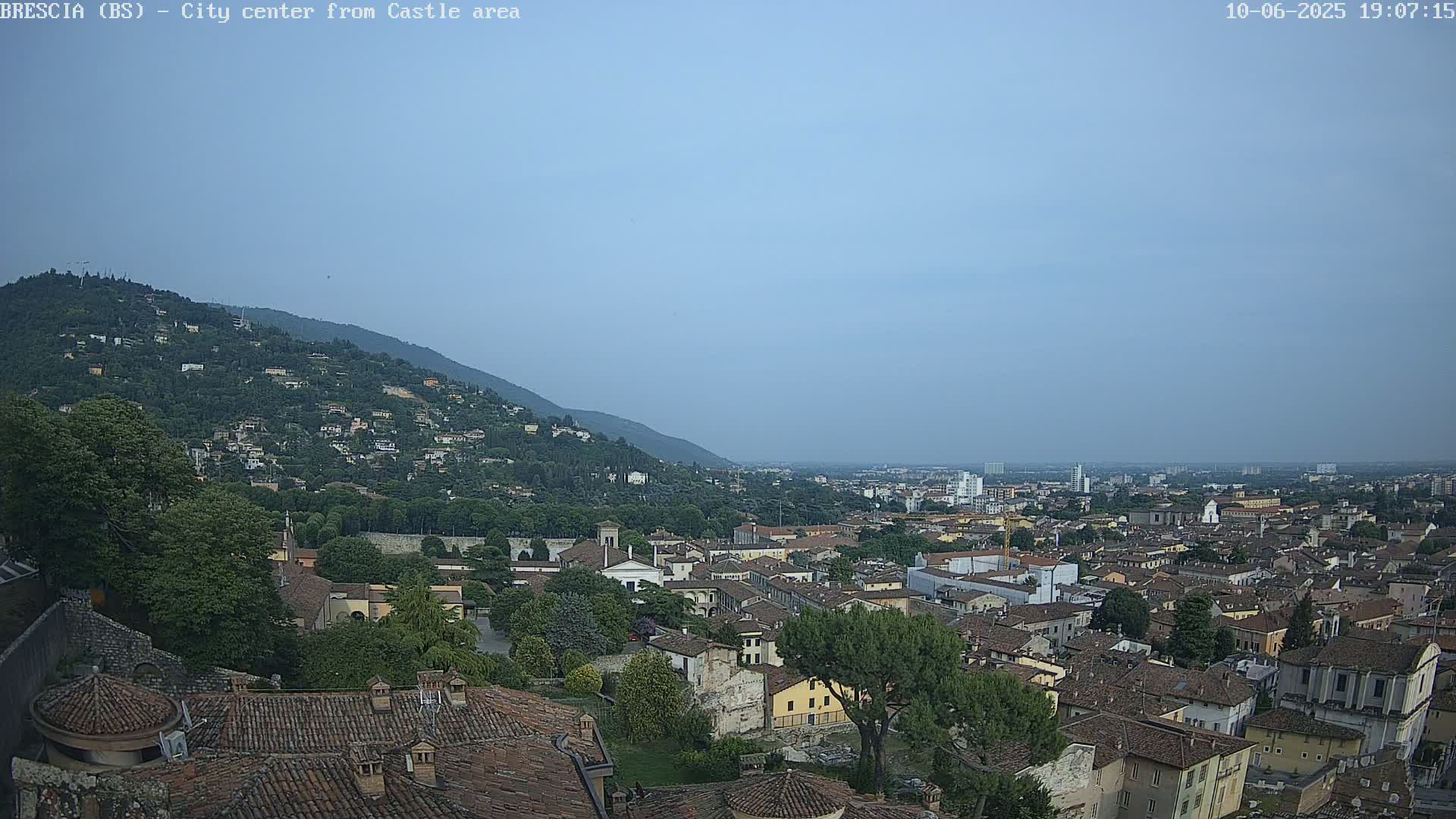 A wide shot of a city nestled at the base of a hill under a hazy sky.