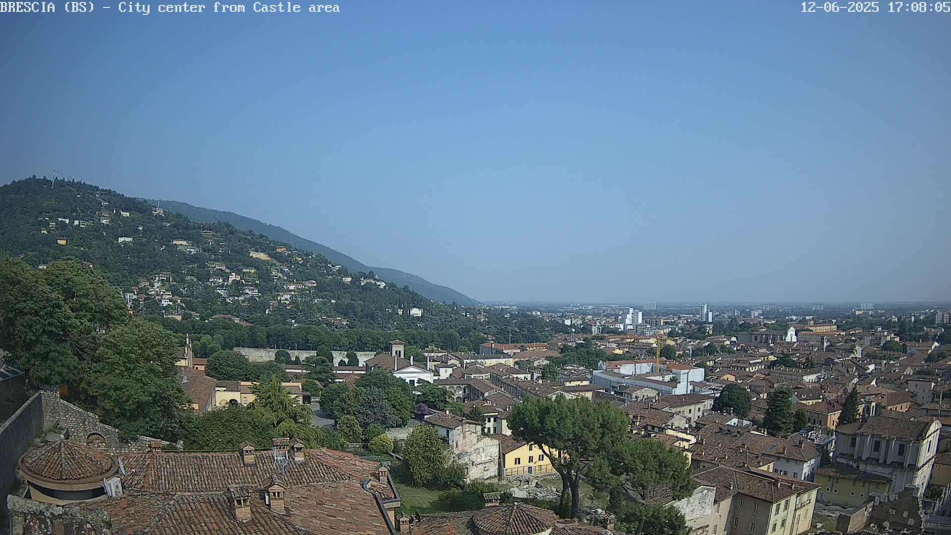 A sprawling city nestled against a mountainside under a clear blue sky.
