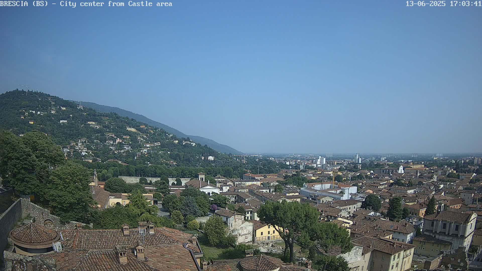 A sprawling city nestled against a mountainside under a clear, blue sky.