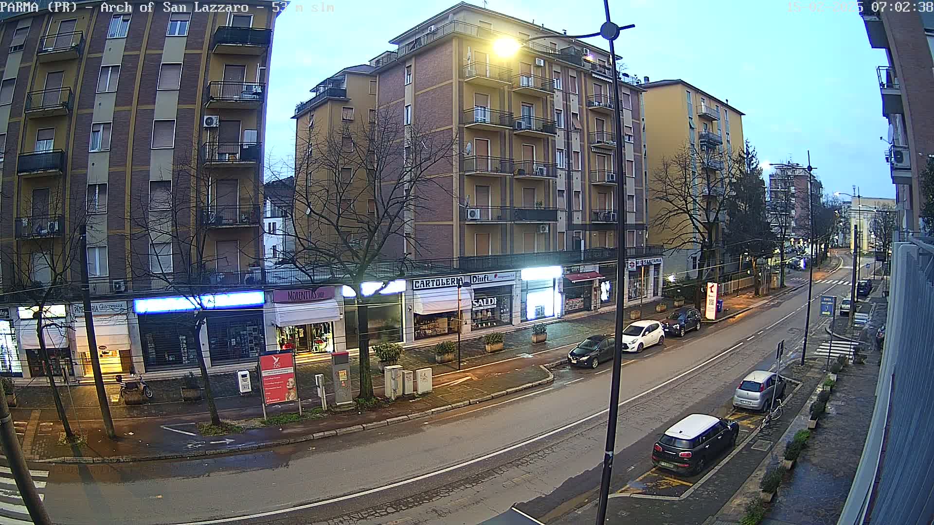 A mostly empty street lined with multi-story buildings and shops under a dusky sky.