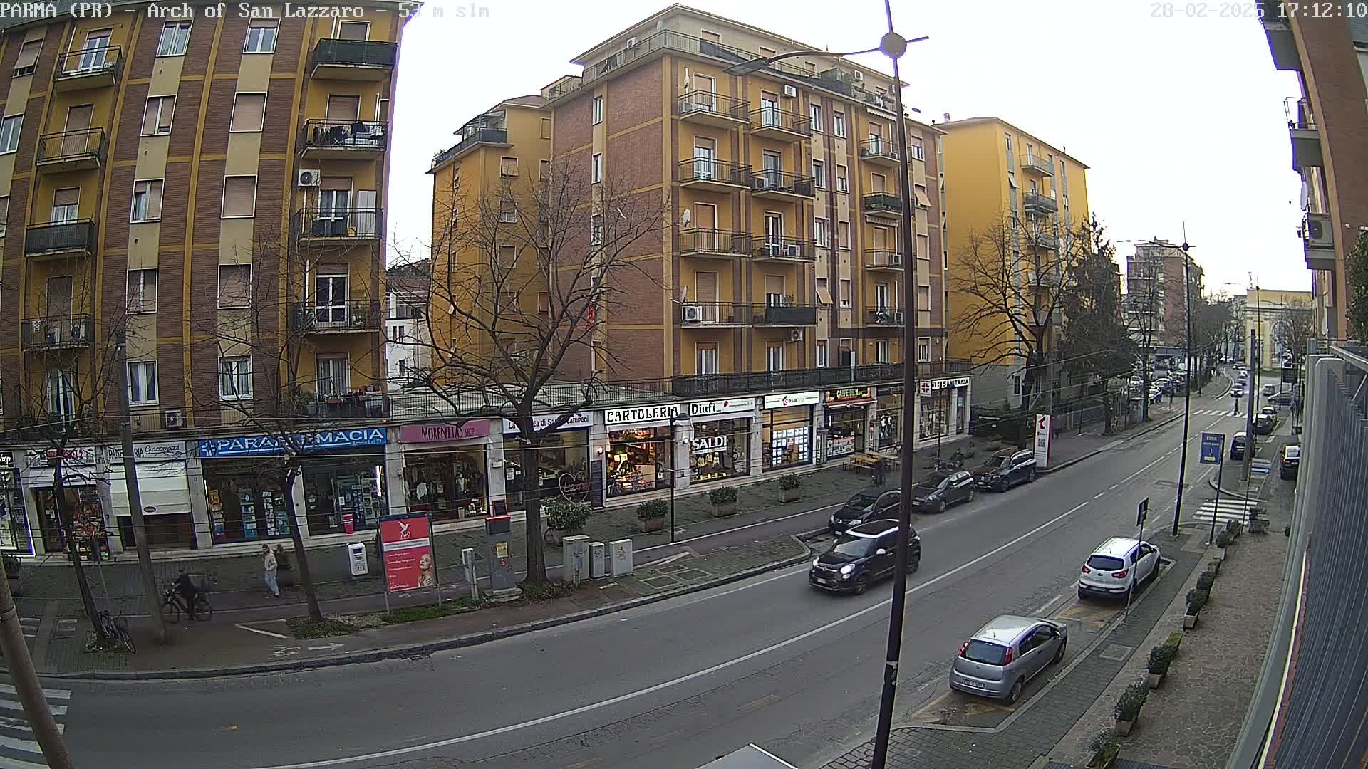A street scene shows several multi-story buildings and parked cars under an overcast sky.