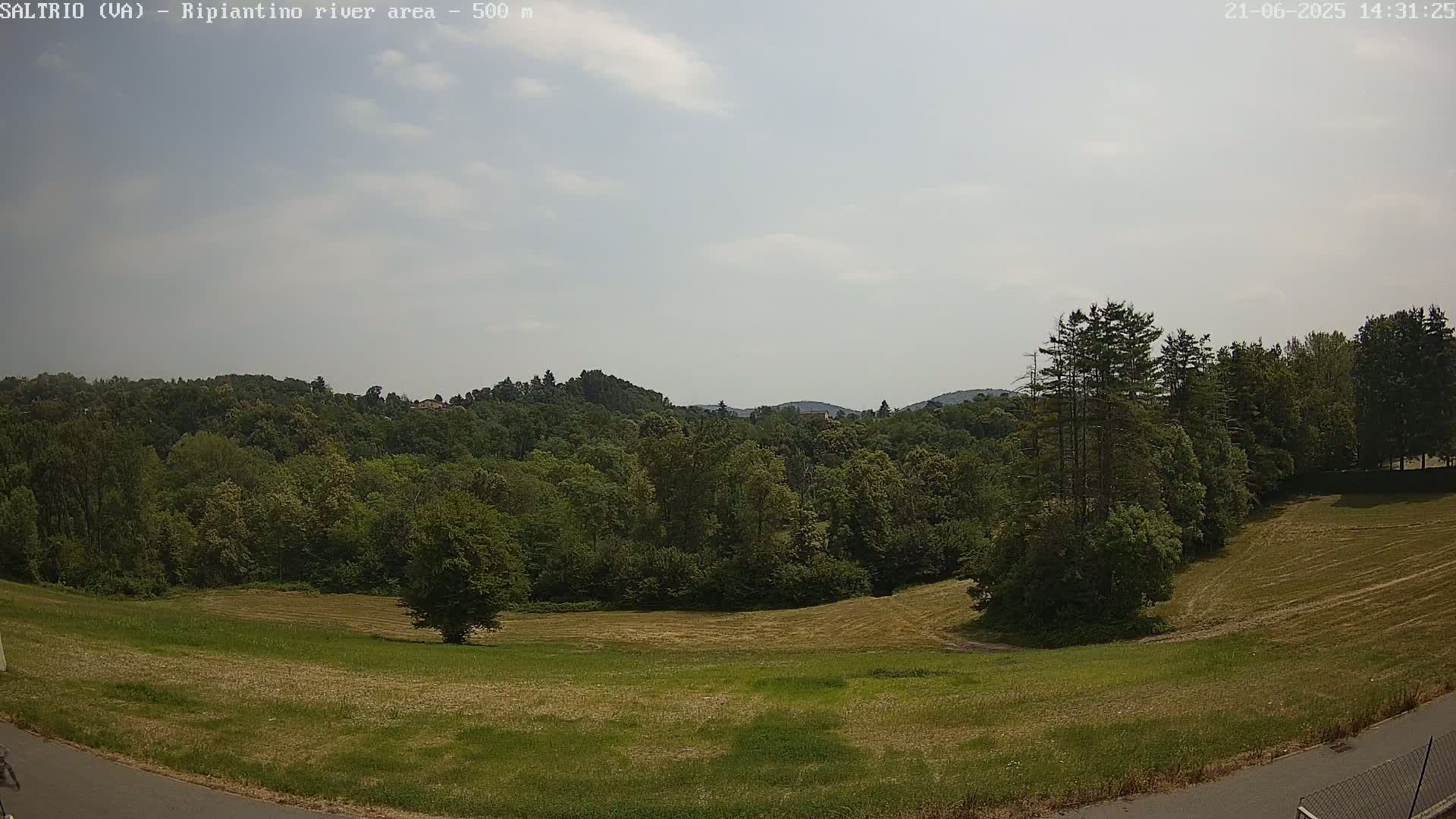 A mostly sunny day reveals a verdant landscape of fields and forests under a partly cloudy sky.