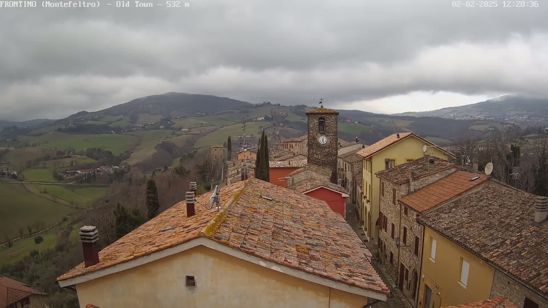 A stone village nestled in rolling green hills under a cloudy sky.