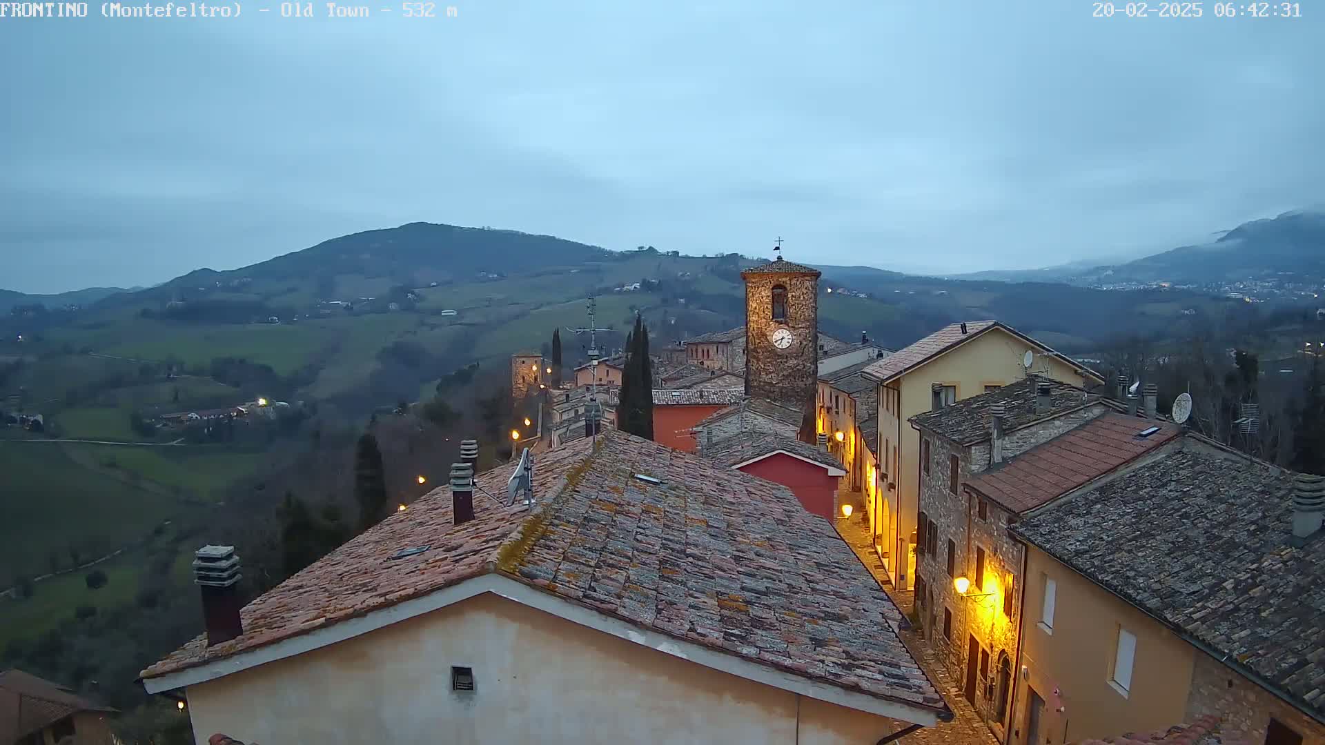 A quaint, stone village nestled in rolling hills under a twilight sky.