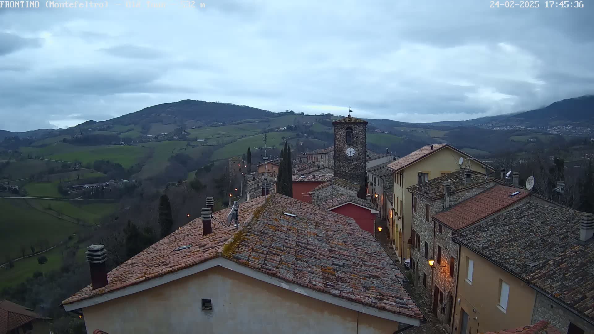 A small town nestled in rolling green hills under a cloudy, overcast sky.