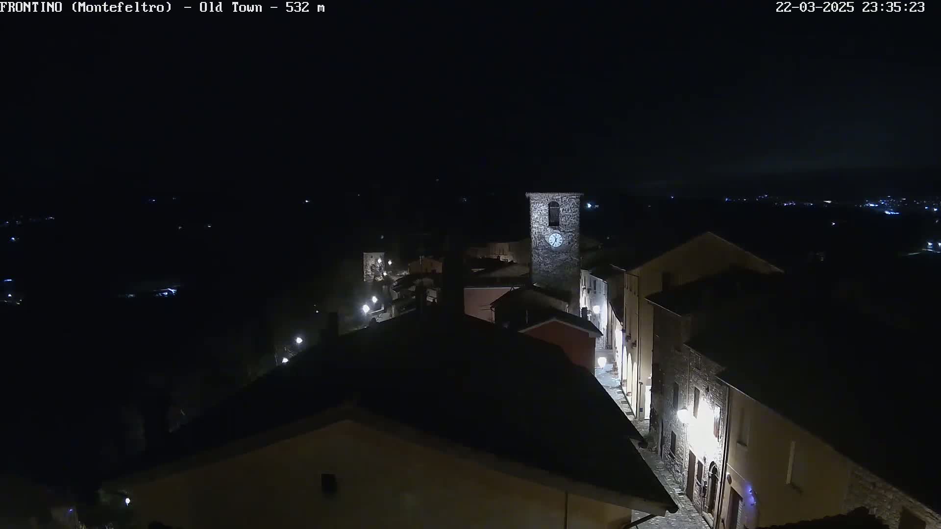 A nighttime, overhead view of a small town's old town with sparsely lit streets and buildings, including a clock tower.