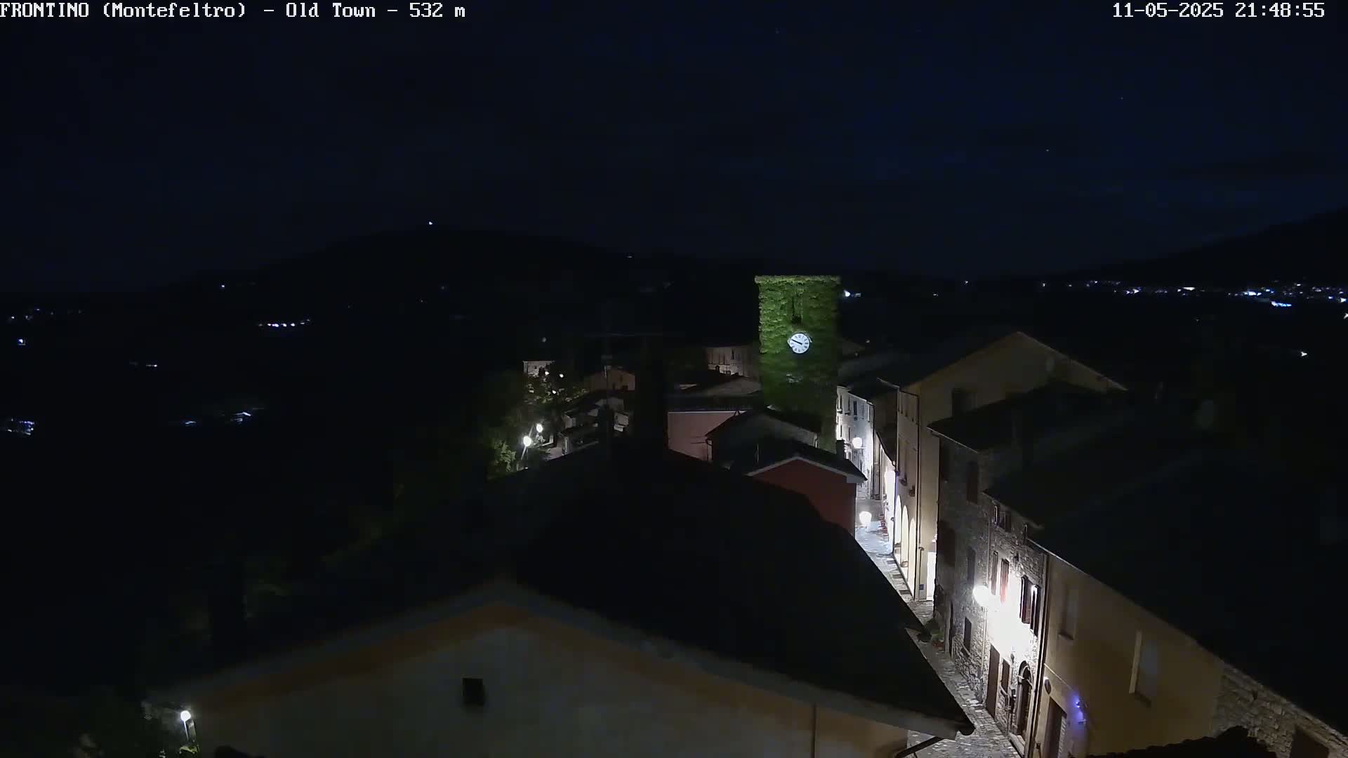 A nighttime, high-angle view shows a small town nestled in a valley under a clear, dark sky.