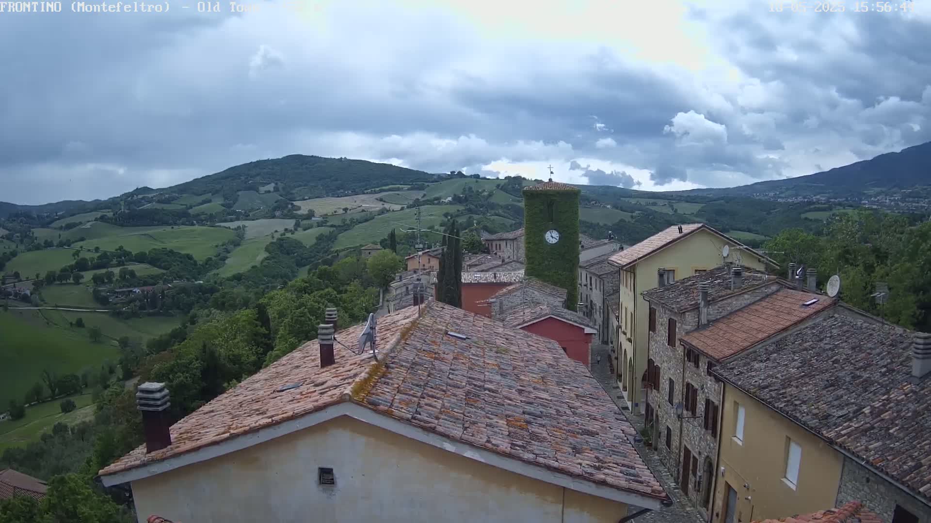 A village nestled in a green valley under a partly cloudy sky.
