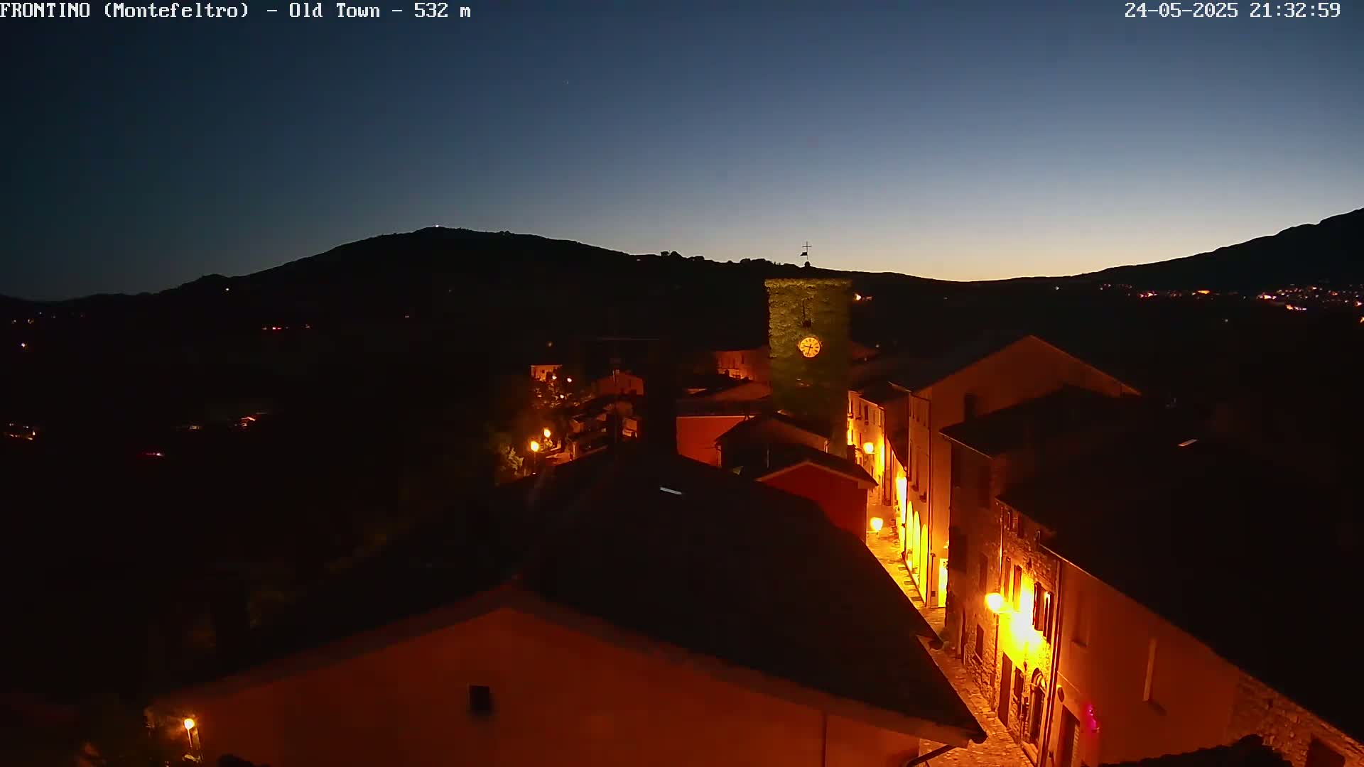 A nighttime view of an illuminated town nestled in a valley under a twilight sky.