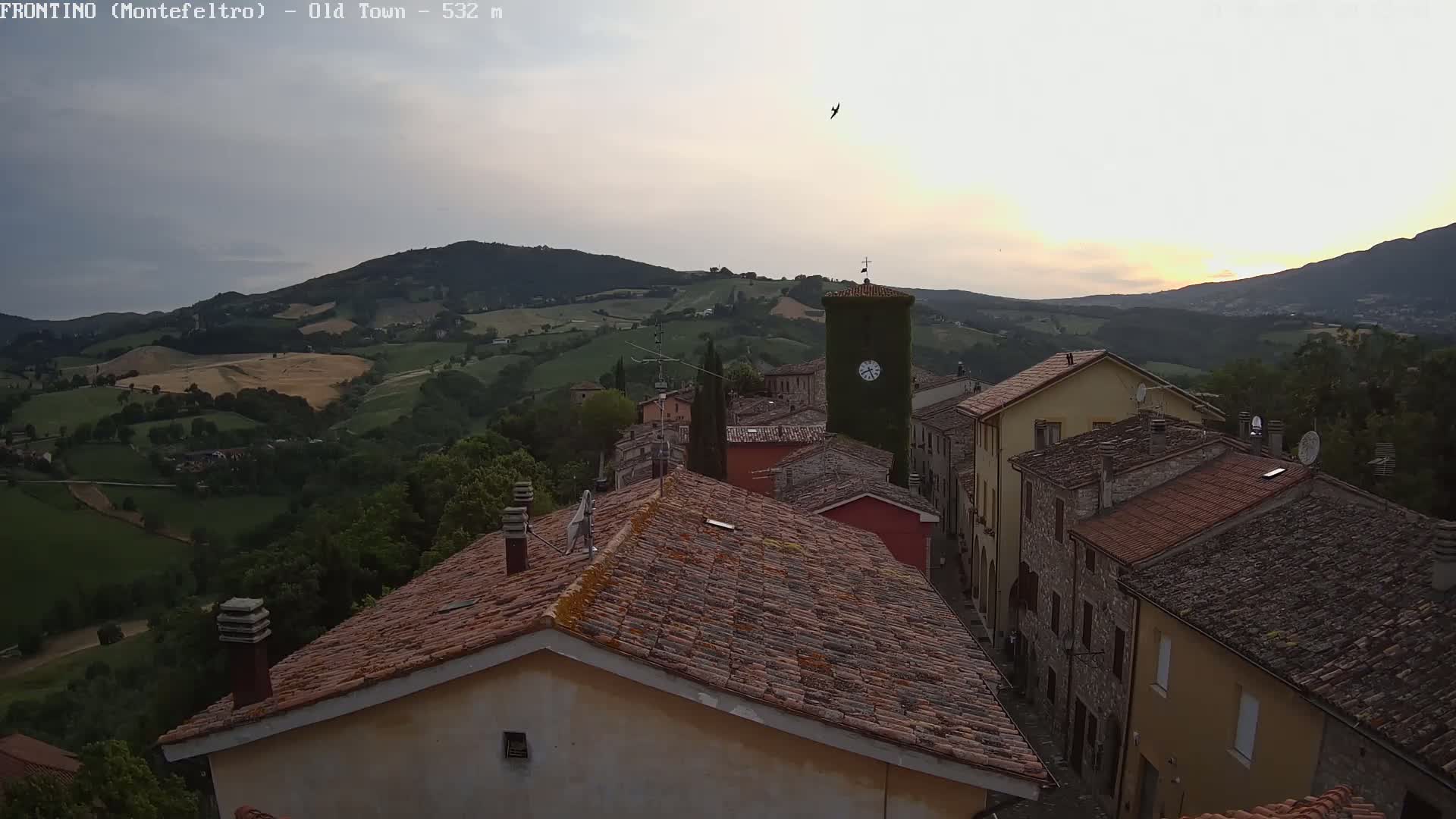 A quaint village nestled in rolling green hills under a soft, sunset sky.