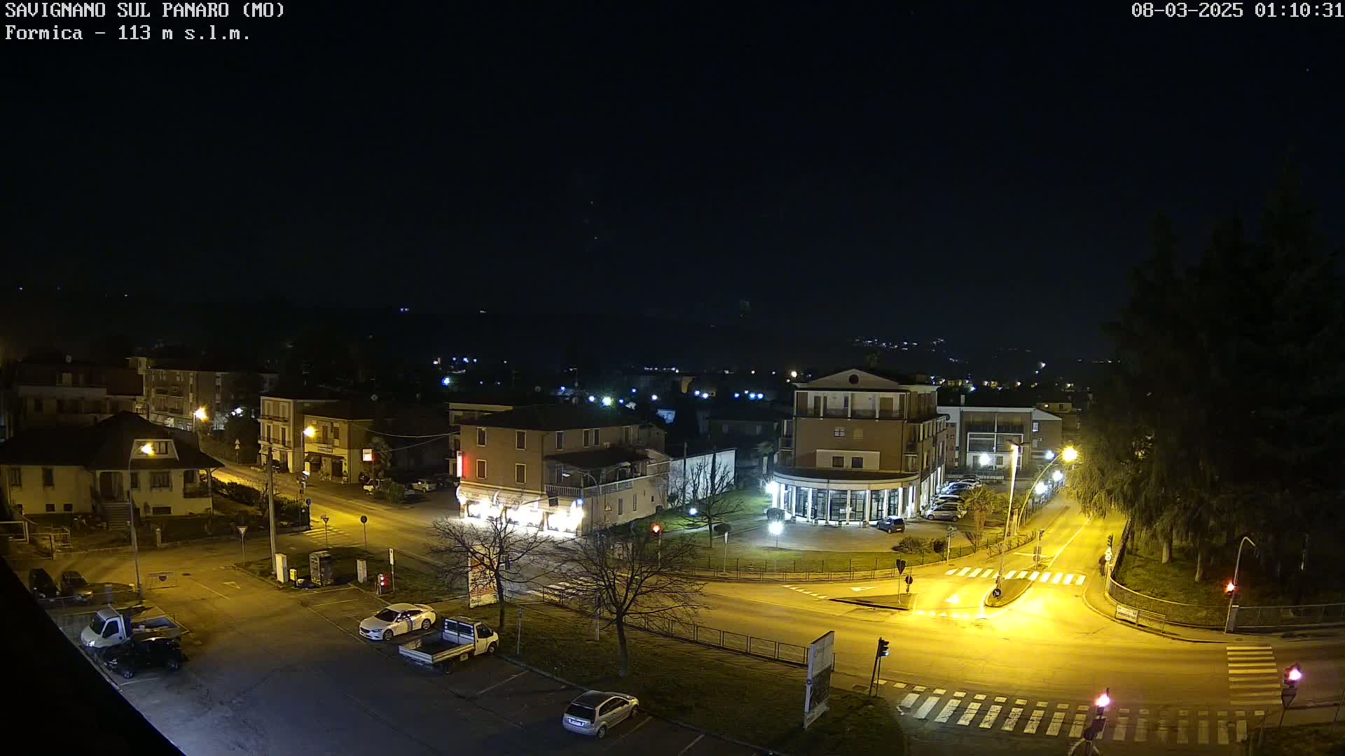 A nighttime aerial view of a town's illuminated streets and buildings under a clear, dark sky.