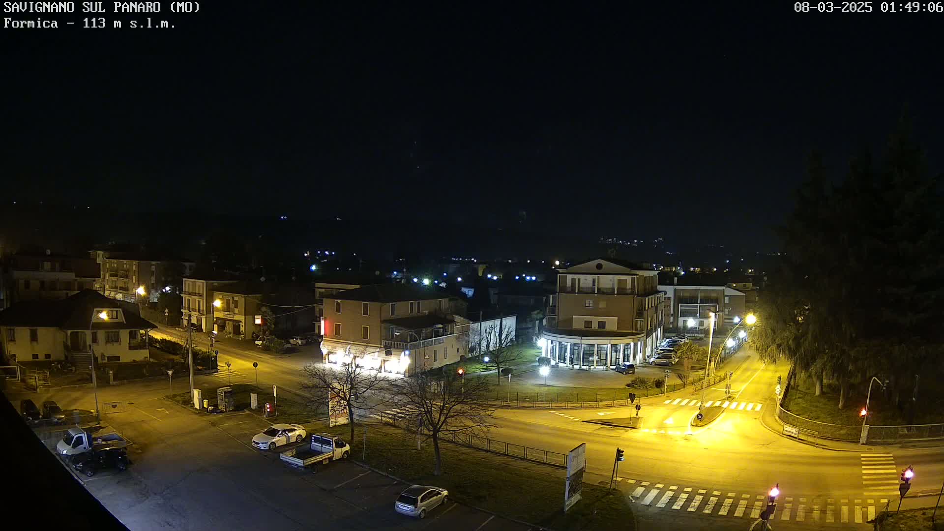 A nighttime aerial view of a town with illuminated streets and buildings, under a clear, dark sky.