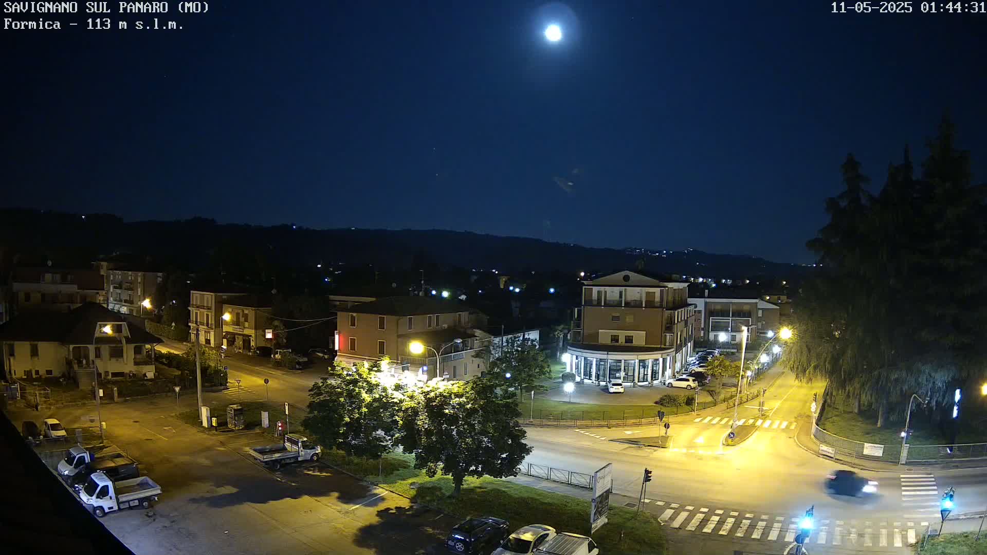A brightly lit intersection in a small town at night under a full moon.