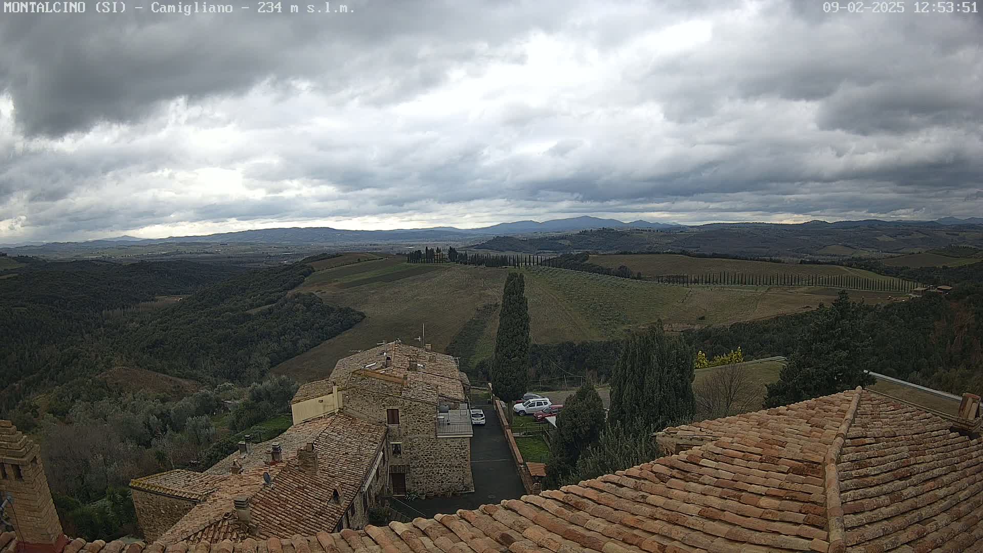Overcast skies overlook a hilly landscape of stone buildings and cultivated fields.