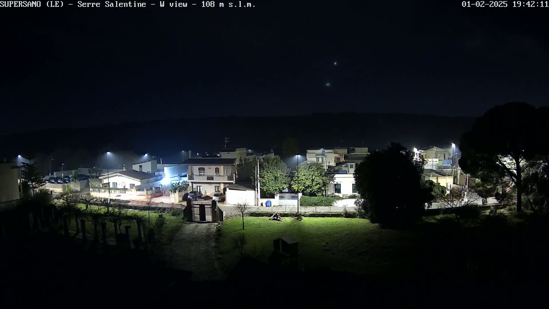A nighttime view of a residential area illuminated by streetlights under a clear, dark sky.