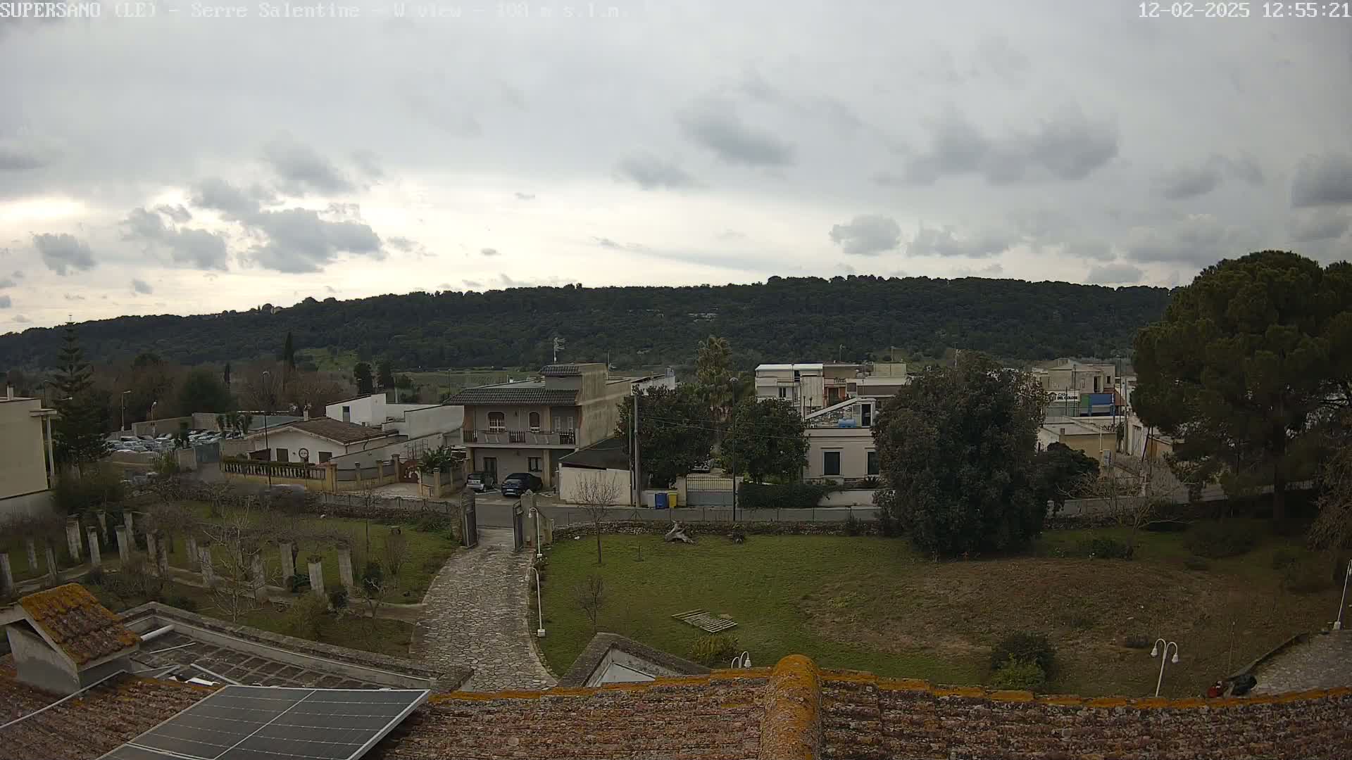 A view of a residential area with a hill in the background under an overcast sky.