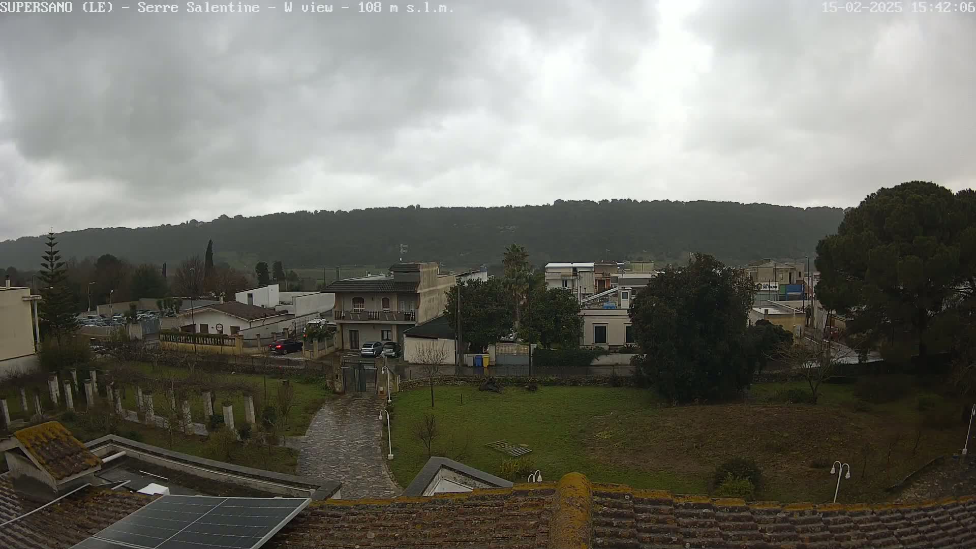 A view of a residential area with overcast skies, showing several buildings nestled against a hillside.