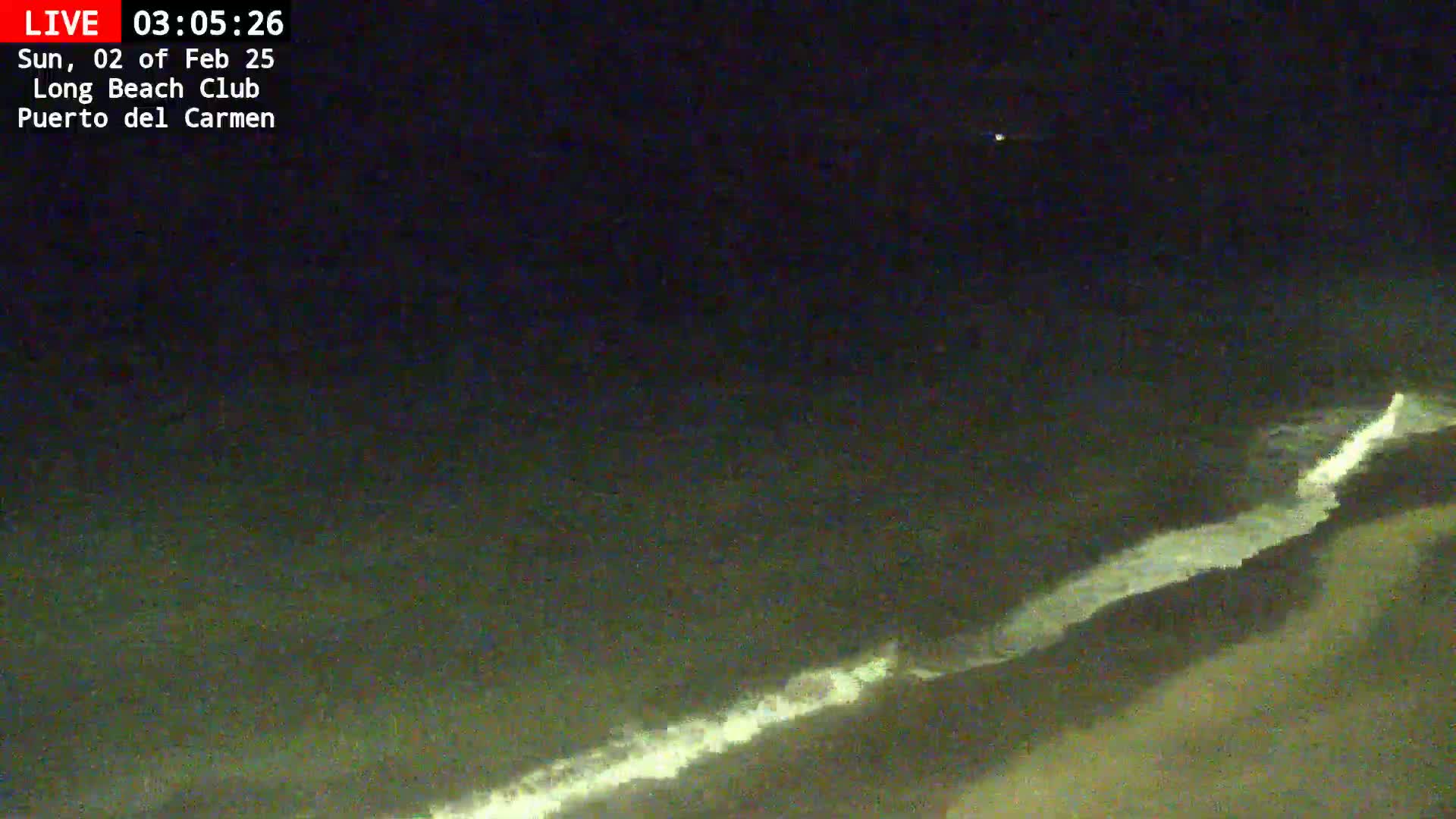 A nighttime long shot shows dark ocean waves breaking on a shoreline under a clear, dark sky.