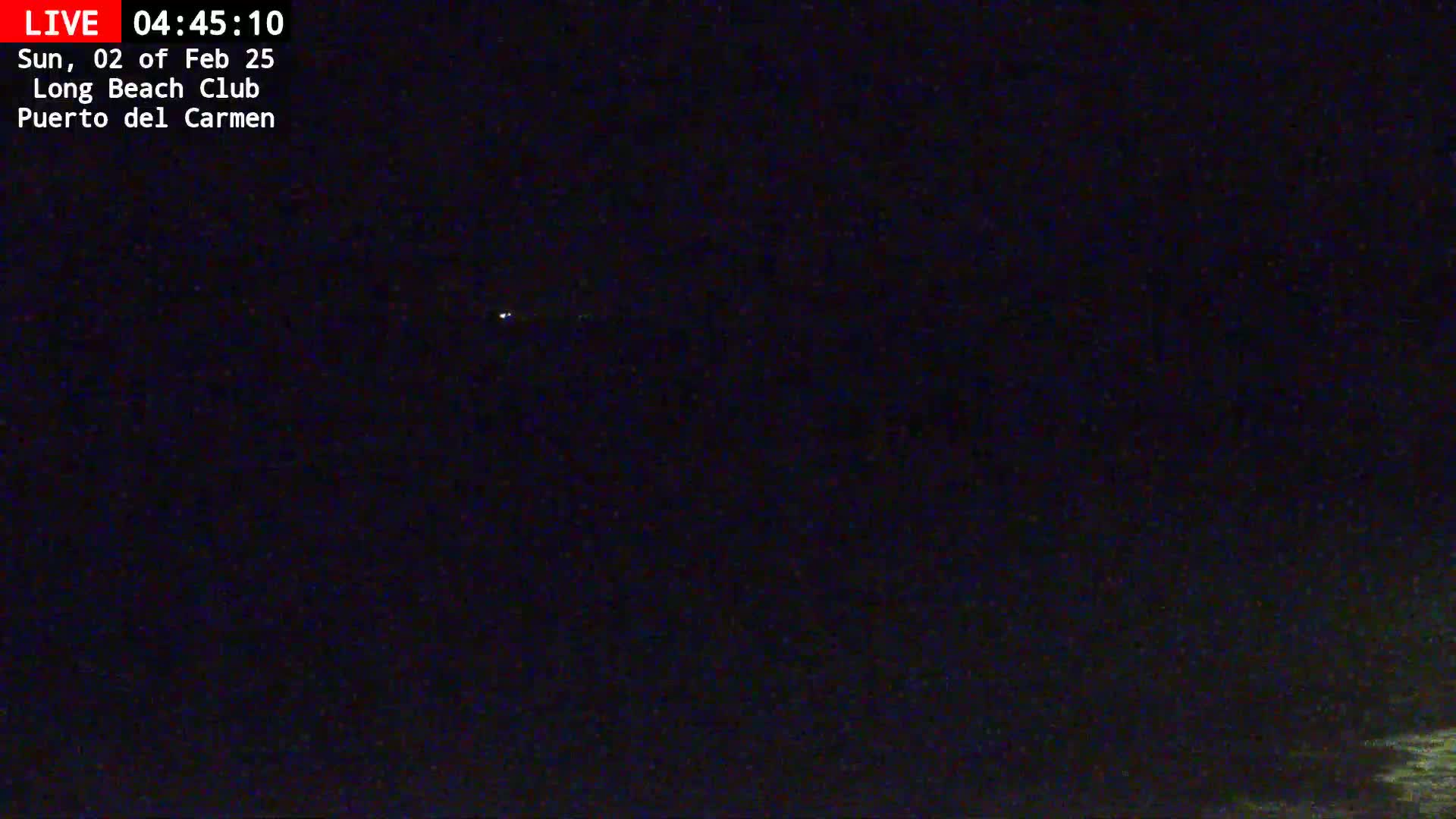 A dark nighttime scene shows a few faint lights in the distance under a clear, starlit sky.