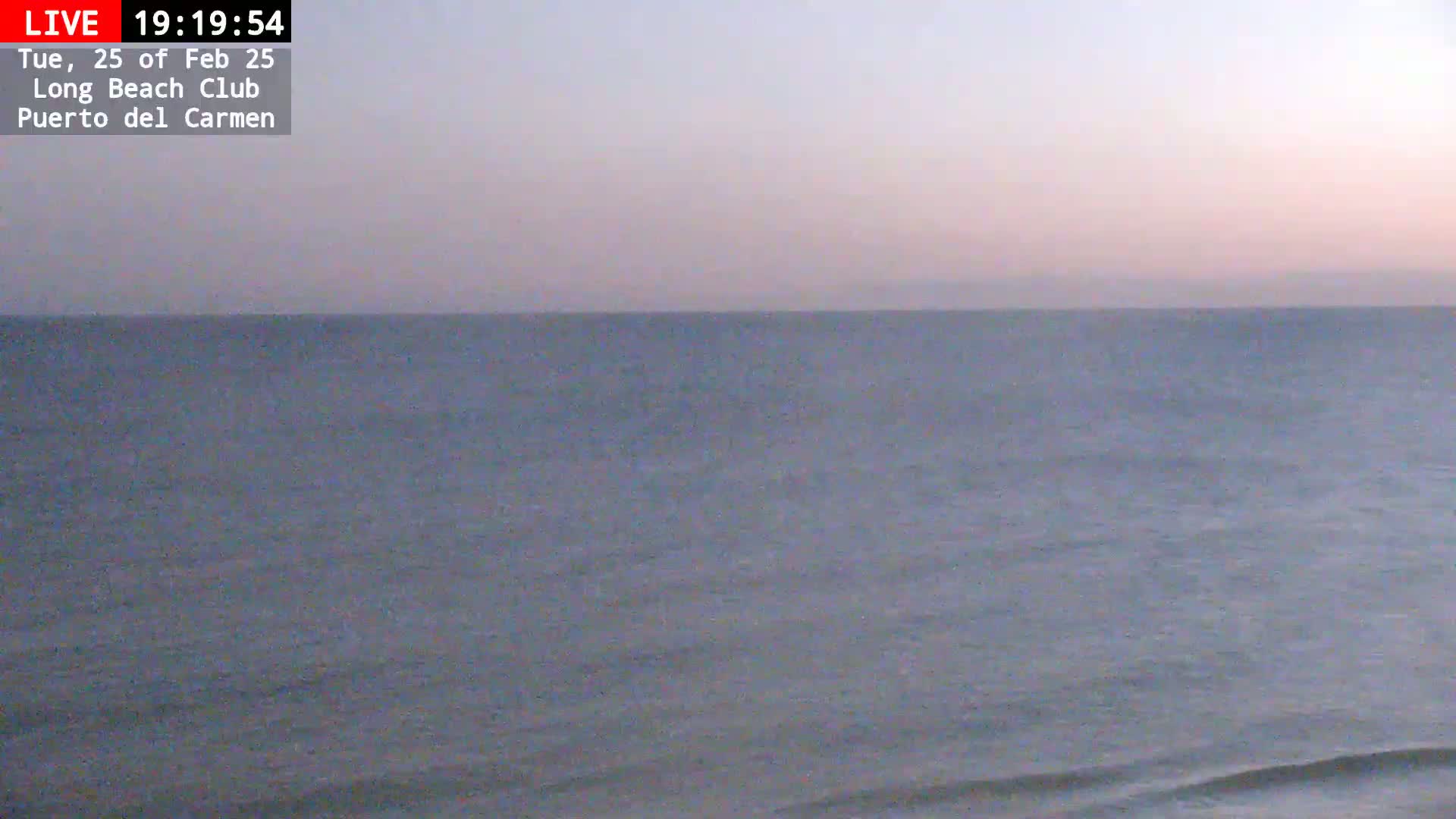 A calm ocean under a pale pink and gray twilight sky.