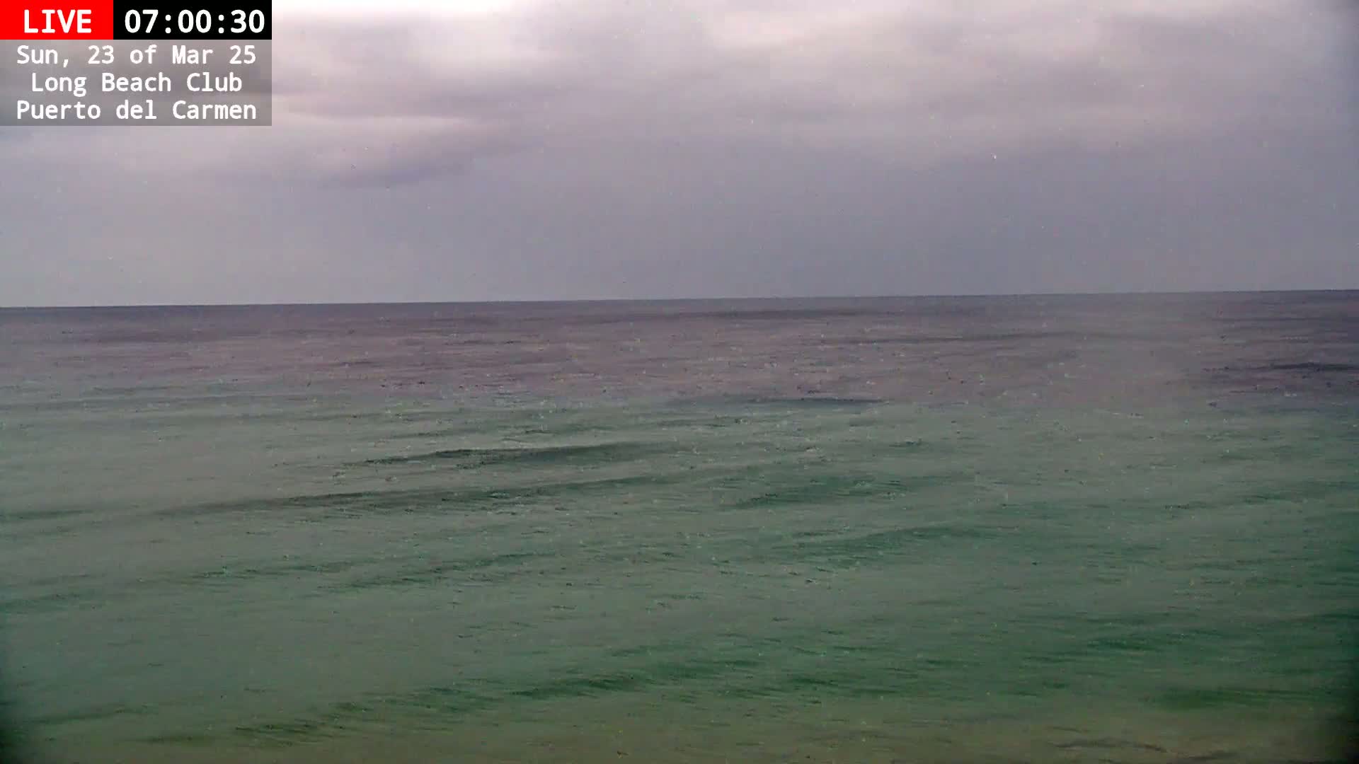 A calm, greenish-blue ocean stretches to the horizon under an overcast sky.