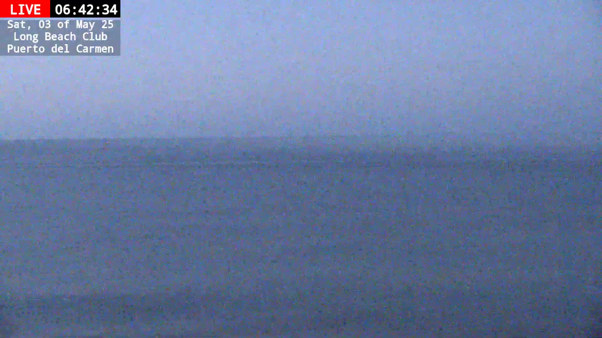 A hazy, overcast view of a calm ocean extends to a distant horizon.