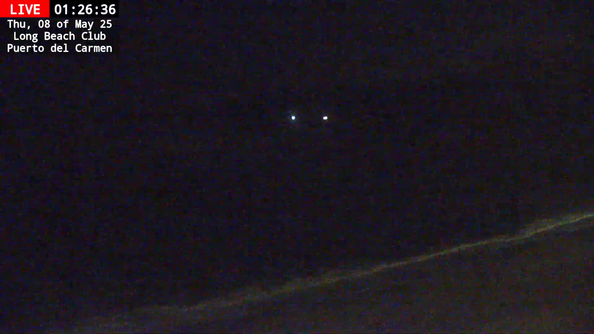 At night, two bright lights appear in a dark sky above a faintly lit horizon.